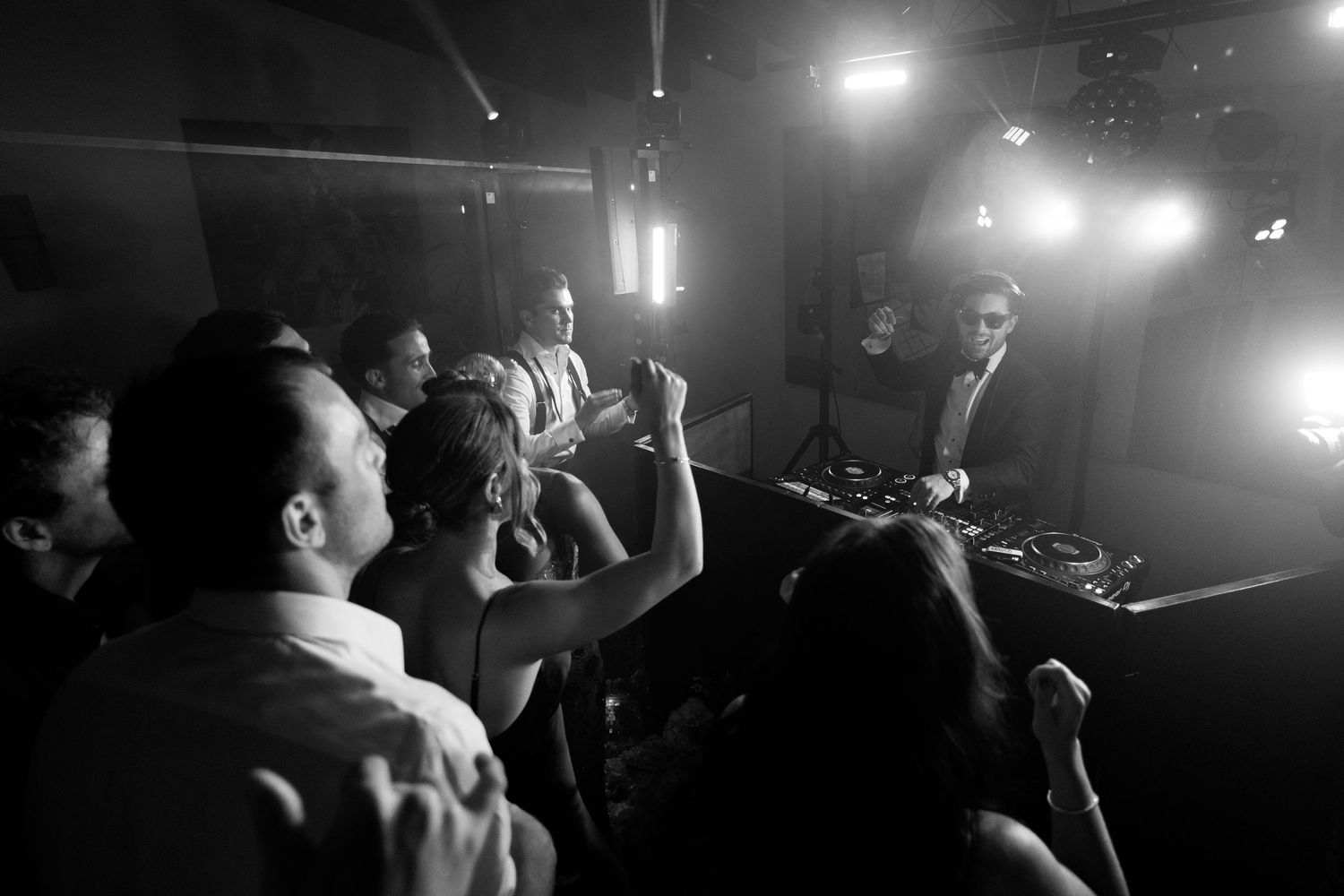 Silhouettes of people dancing at a wedding reception with dramatic backlighting and smoke effects.