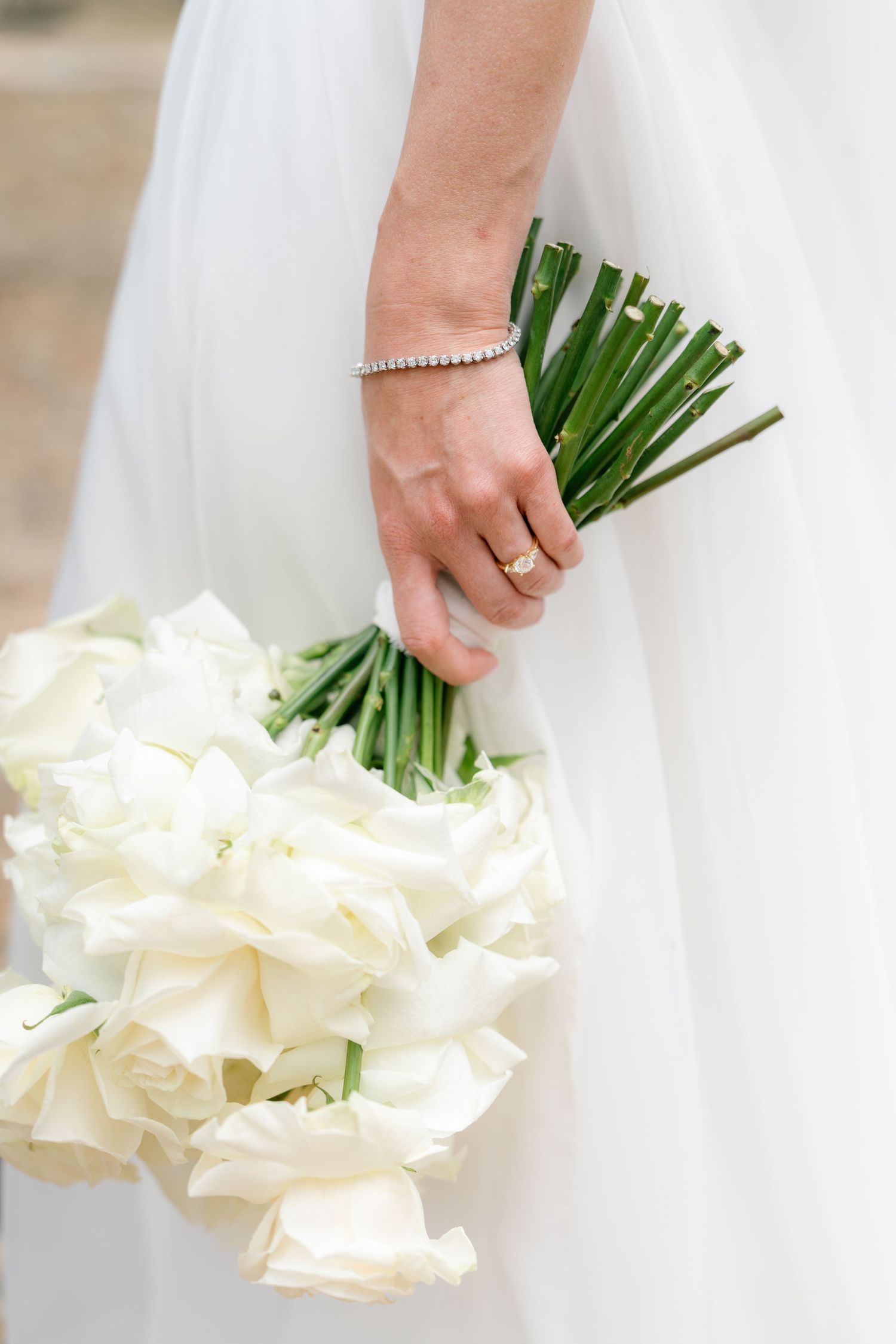 Elegant white calla lily bouquet held against a flowing wedding dress.
