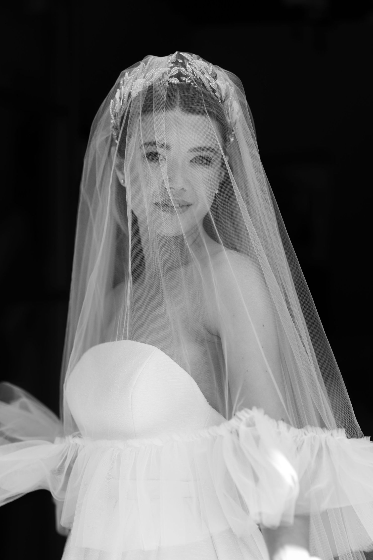 Ethereal bridal portrait with delicate veil creating a romantic silhouette.