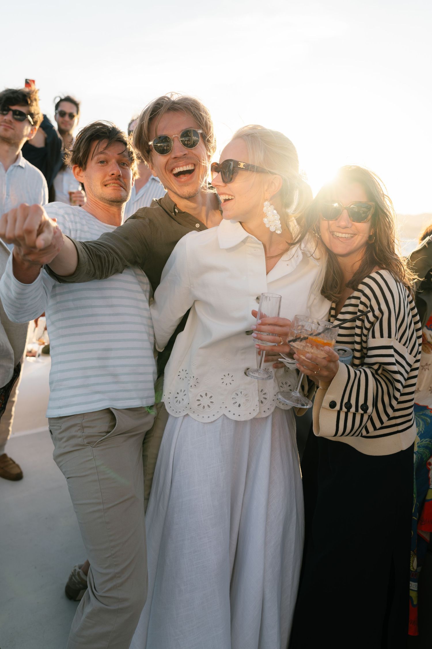 Group of people celebrating on a boat during sunset wearing casual summer attire.