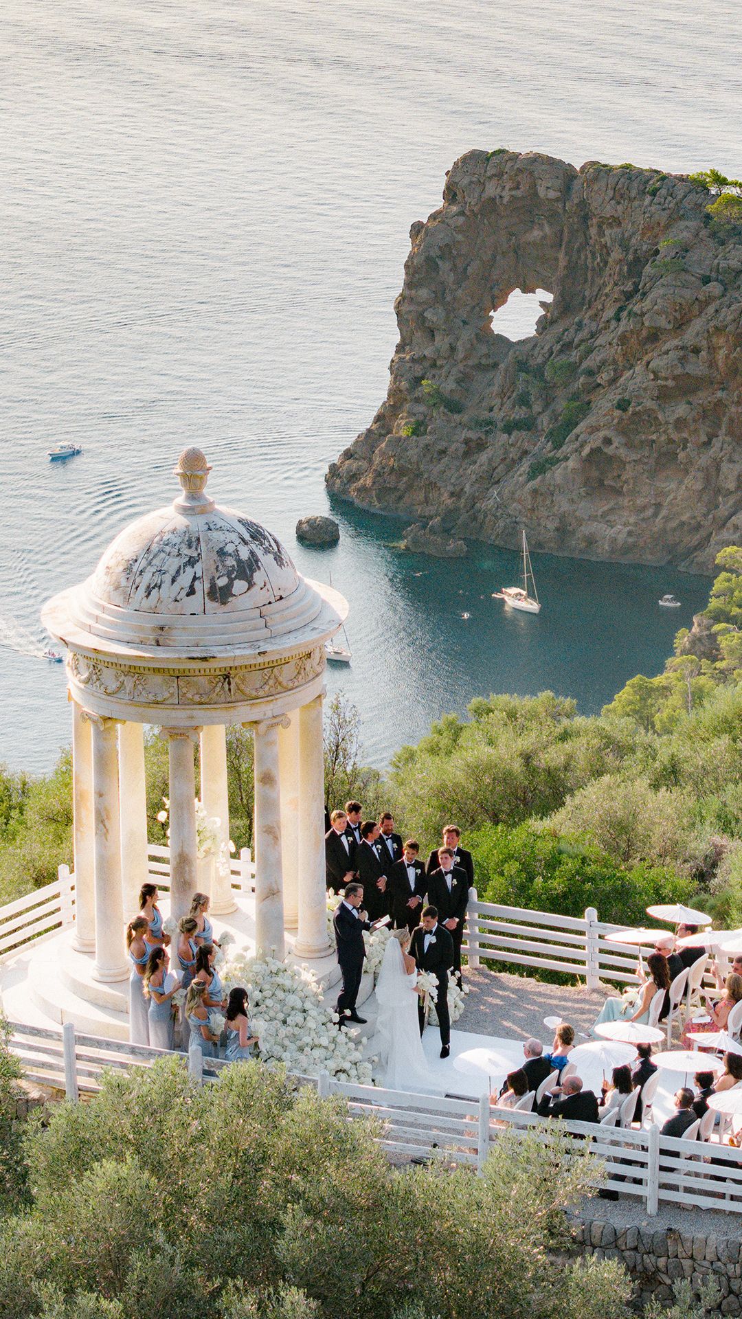 Elegant outdoor wedding ceremony at a cliffside venue in Mallorca, featuring a white rotunda overlooking the stunning Mediterranean Sea.