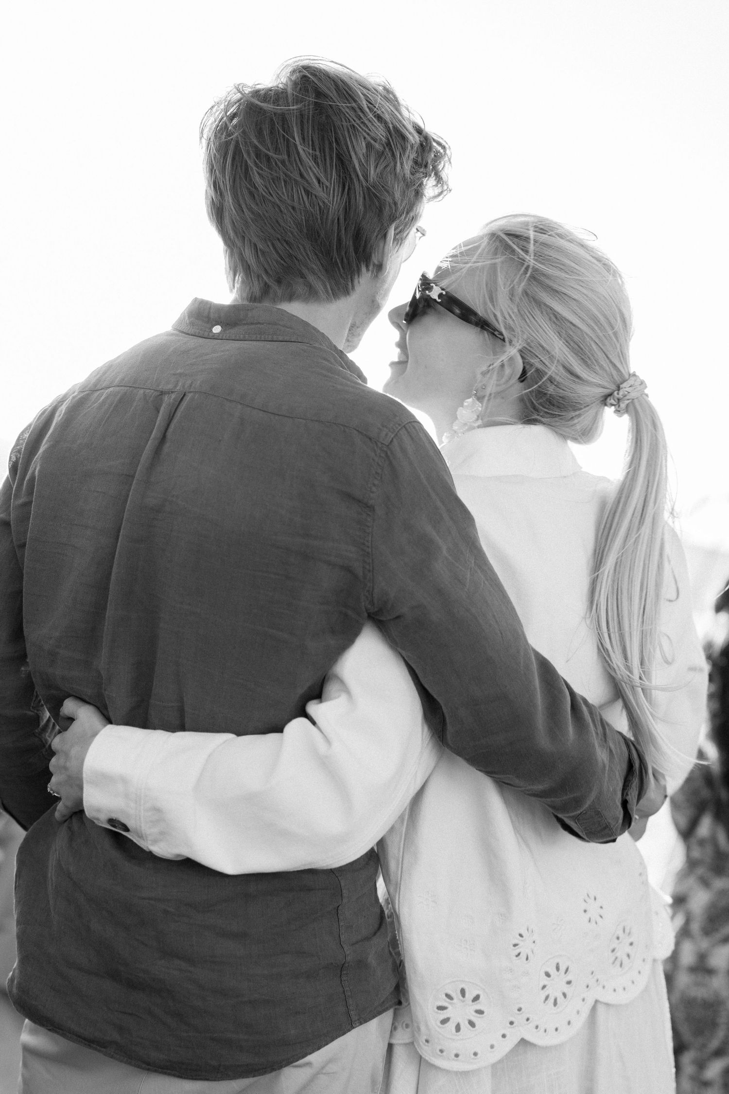 Black and white photo showing a line of people embracing with arms around each other.