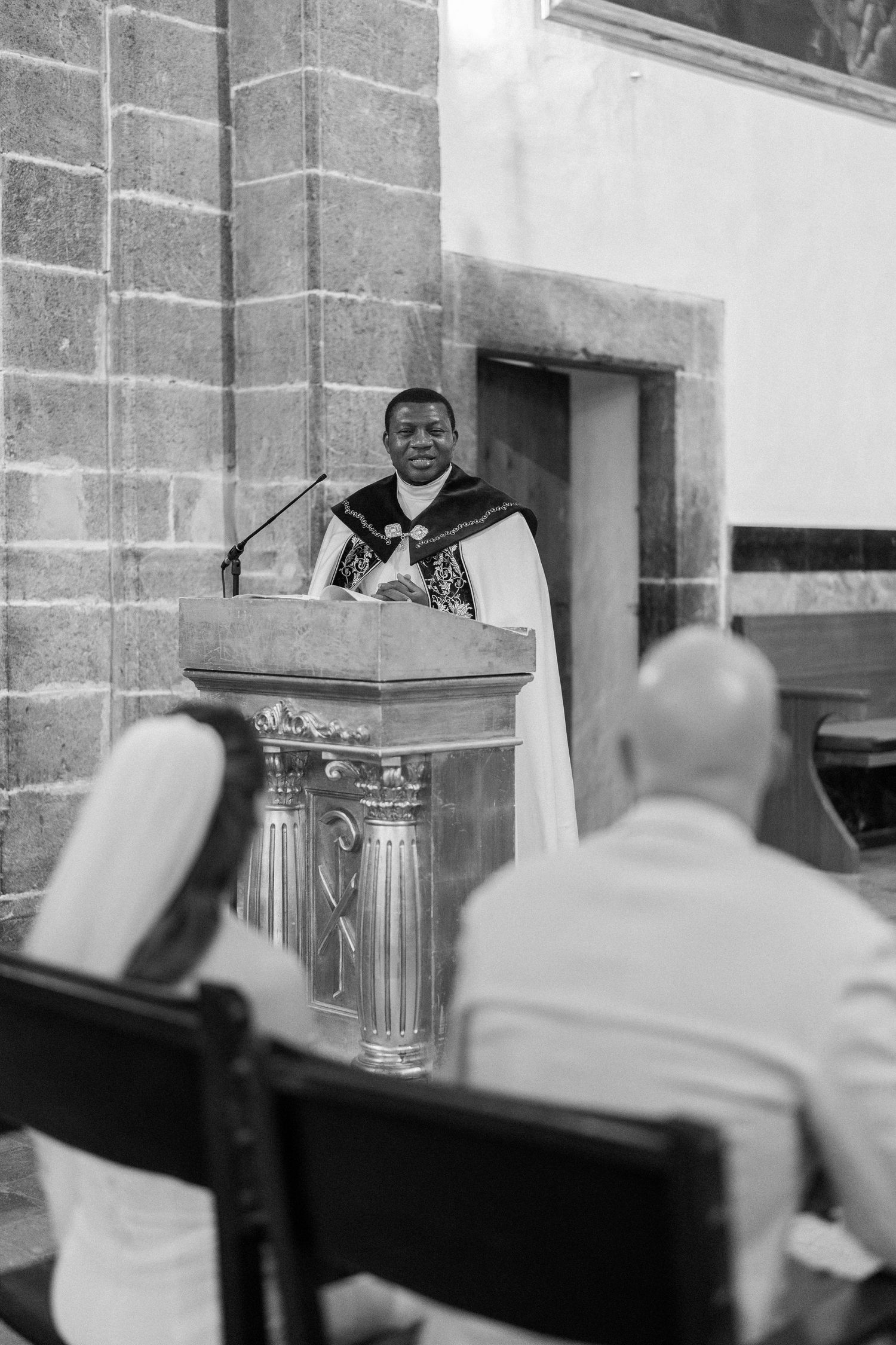 Black and white interior shot of a church ceremony with stone architecture.