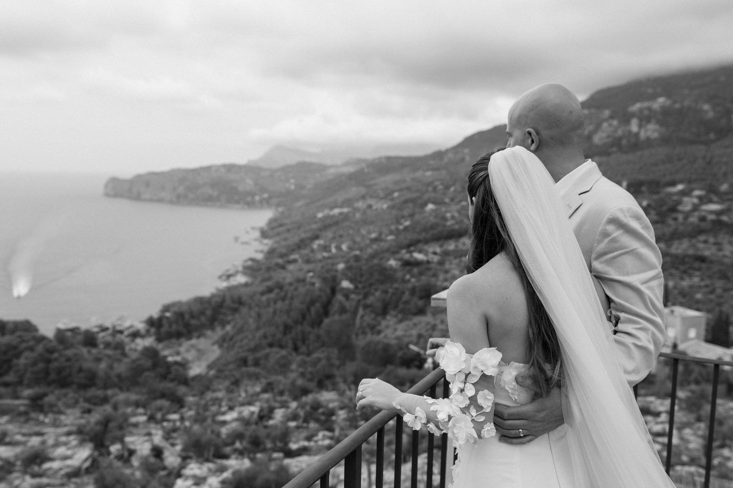 Wedding couple embracing with dramatic coastal mountain landscape view.
