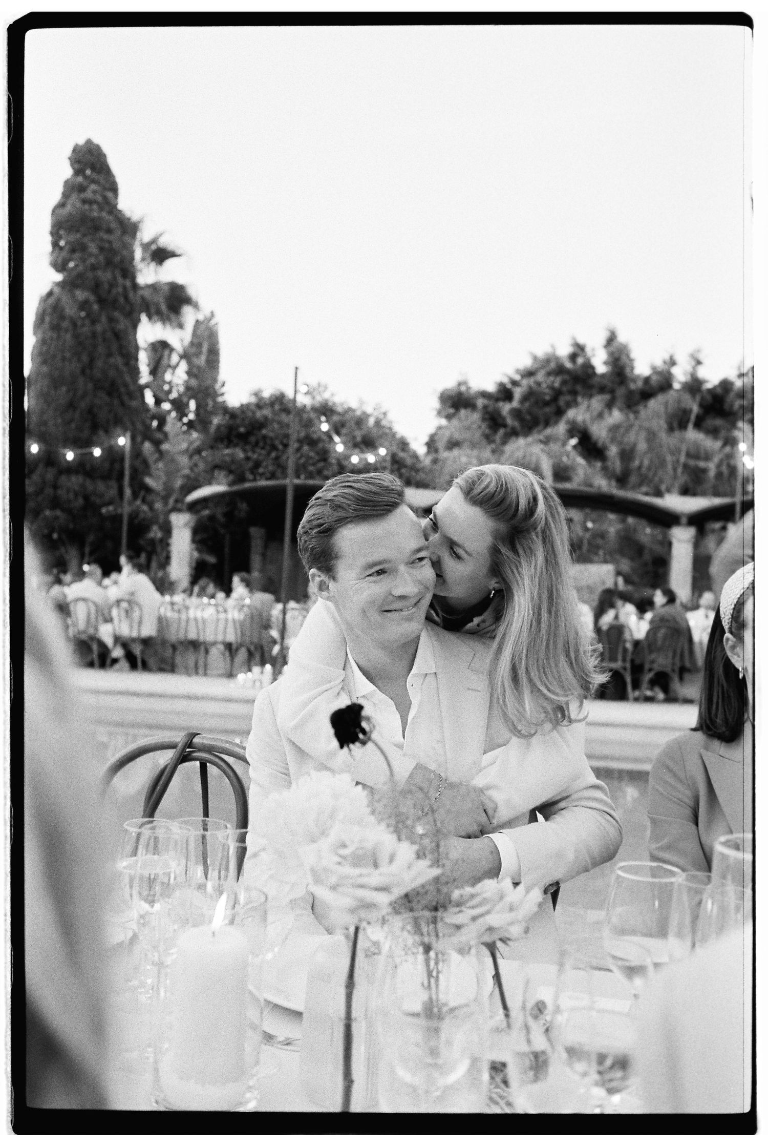 Candid reception moment at outdoor wedding with guests seated at tables with wine glasses.