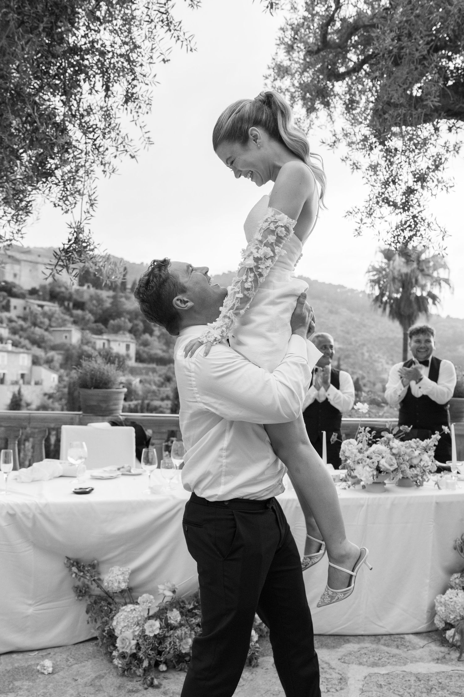 Black and white photo of a romantic lift during a wedding dance on a terrace.