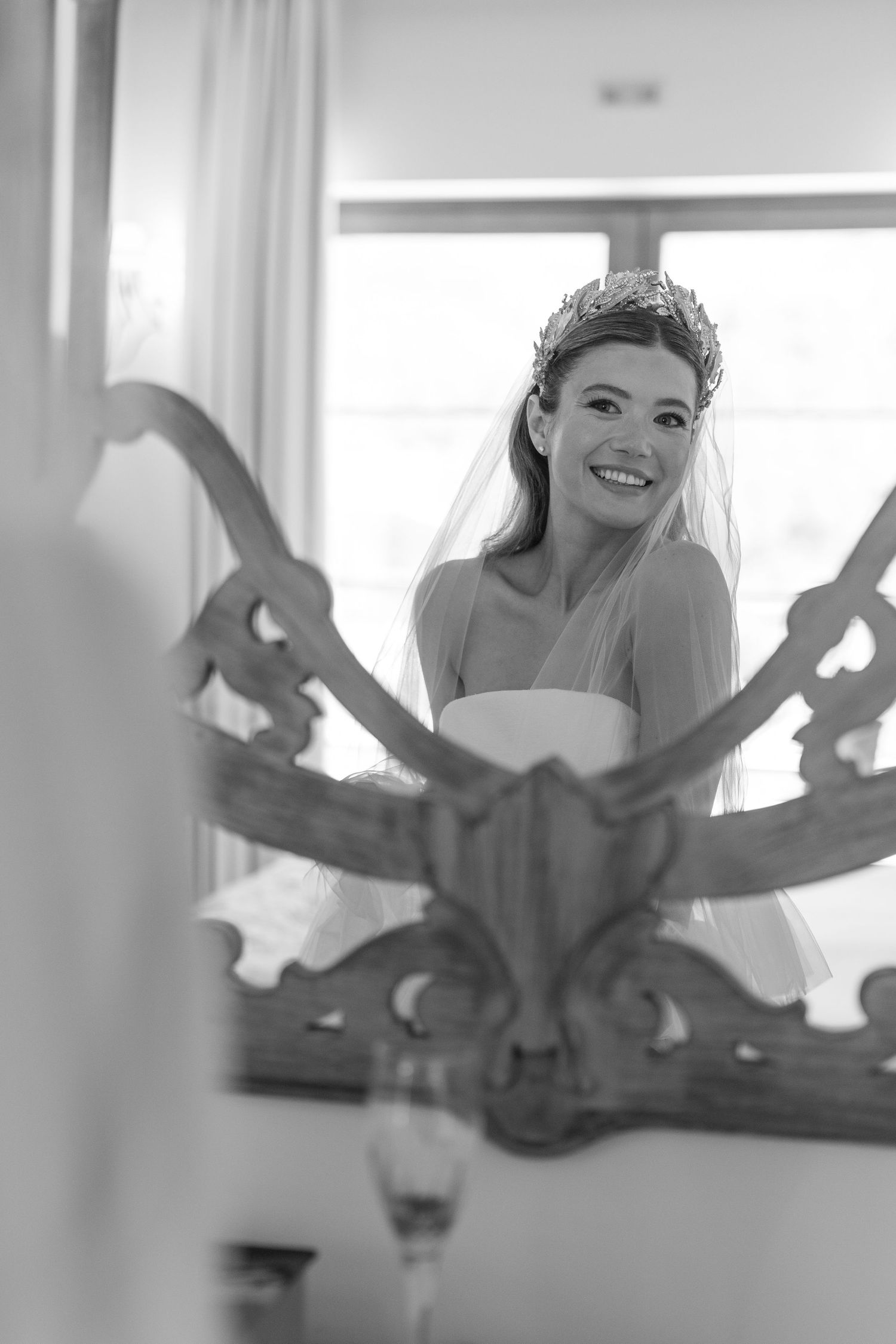 Black and white image showing playful wedding preparation moments through window reflections.