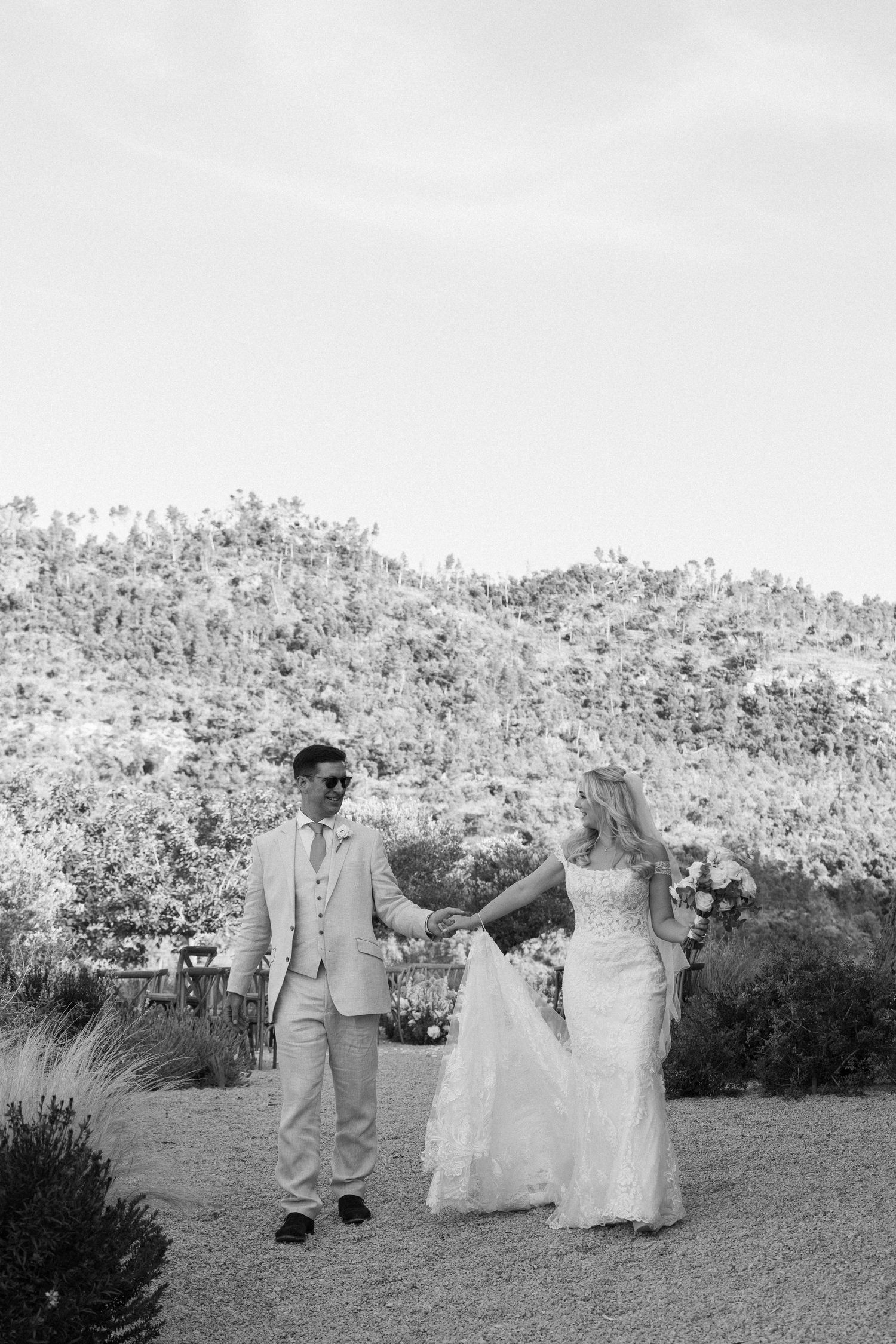 Wedding couple walking through garden landscape in black and white photography.