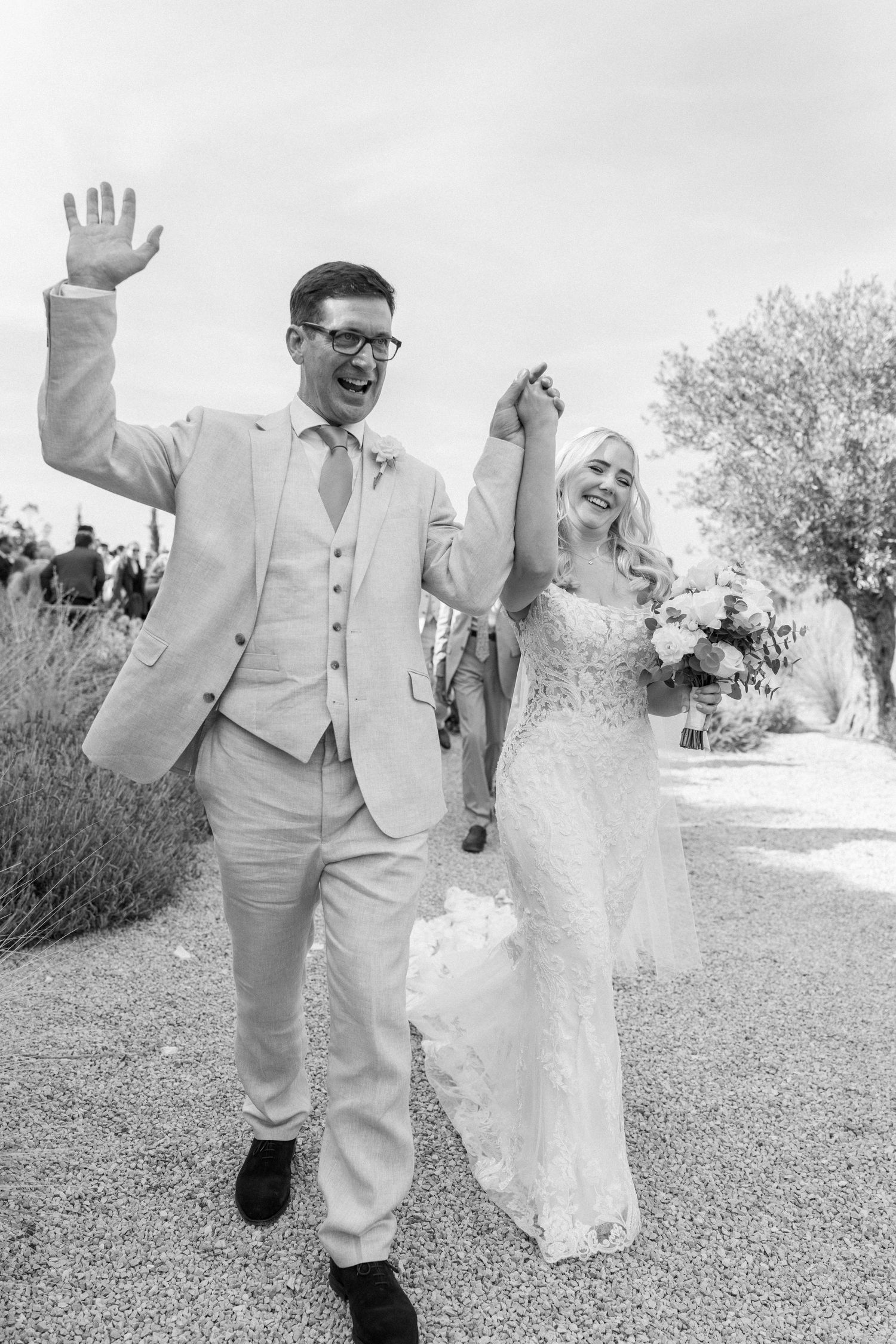 Joyful wedding couple dancing and celebrating on a garden path.