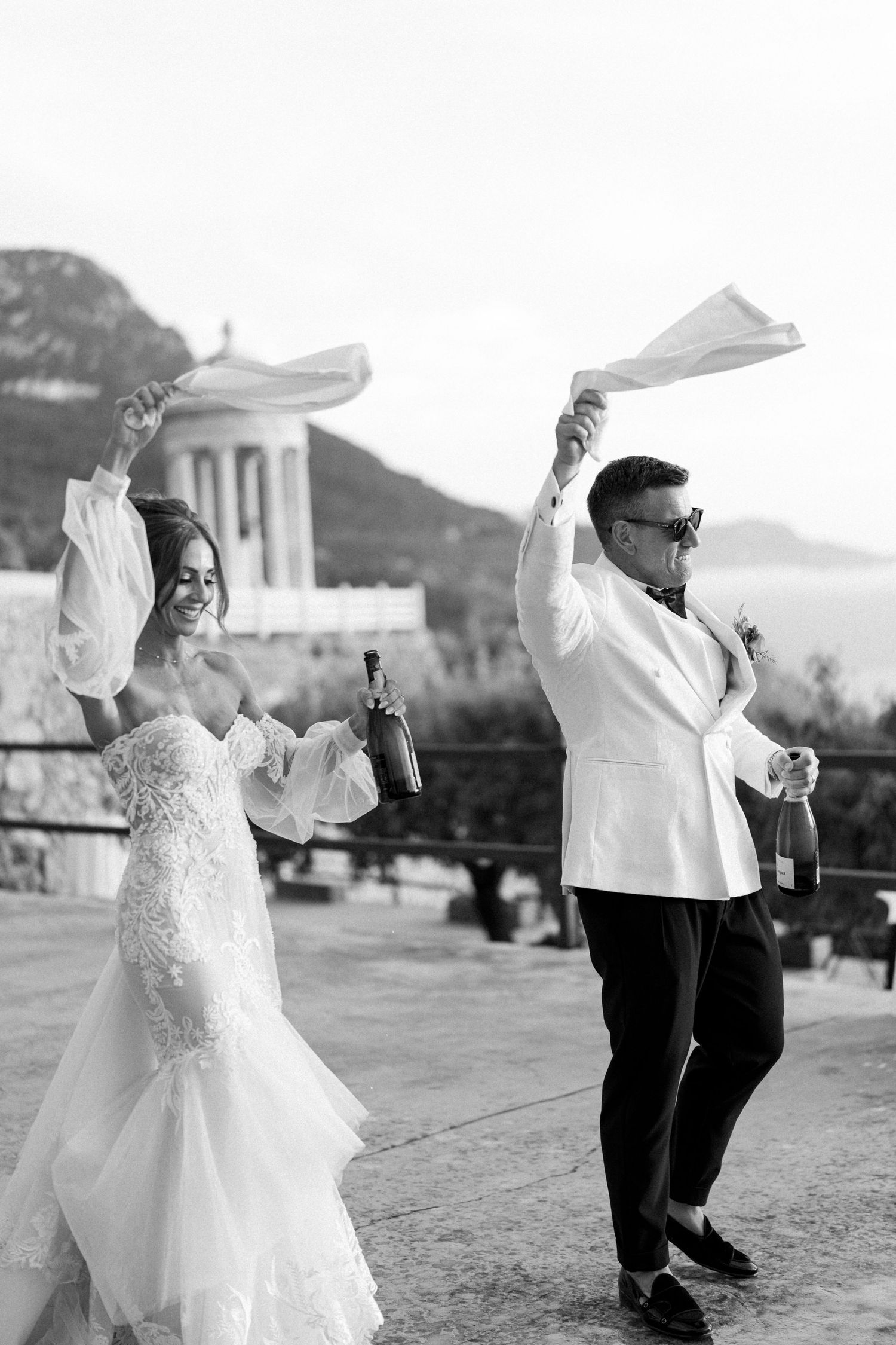 A couple in wedding attire dances joyfully together in a series of black and white photos outdoors.
