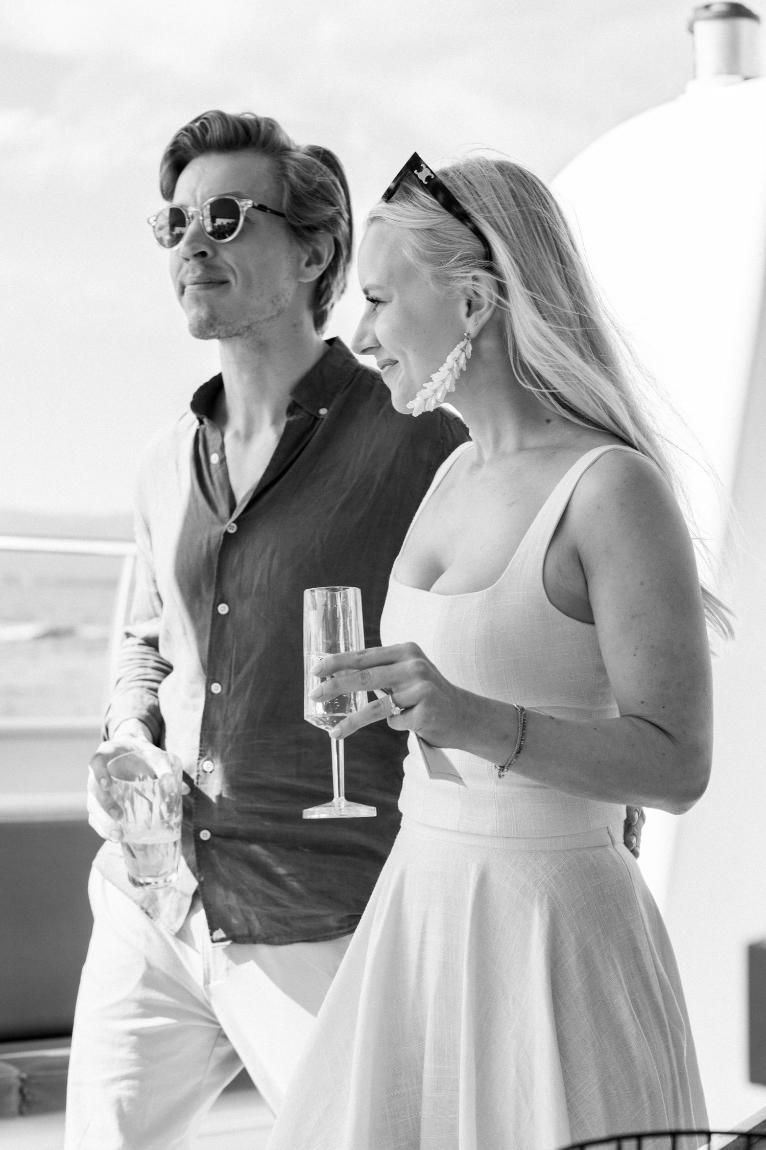 Guests in summer attire enjoying drinks and conversation on a boat deck.