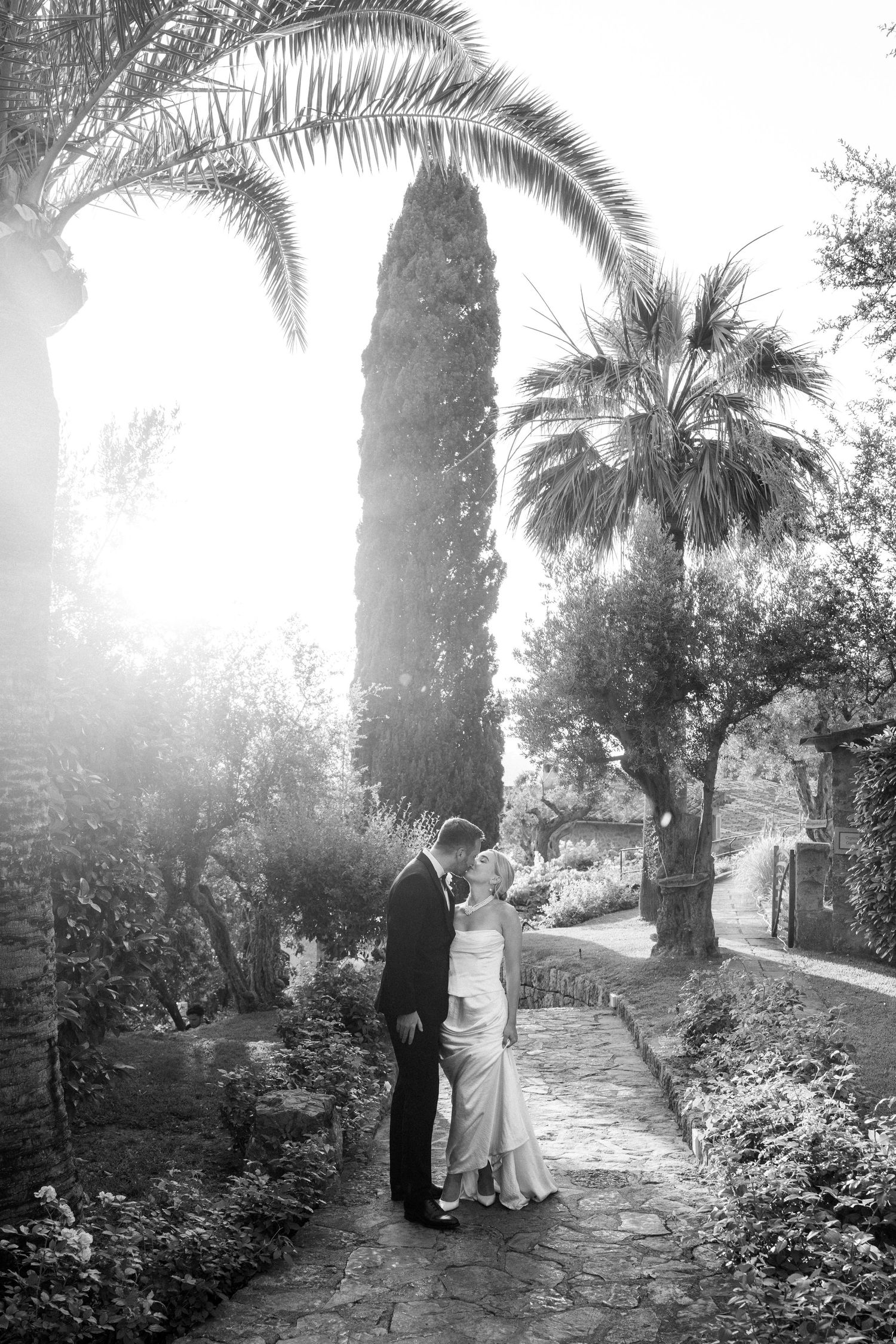 Black and white wedding photos on a palm-lined path create a romantic atmosphere.