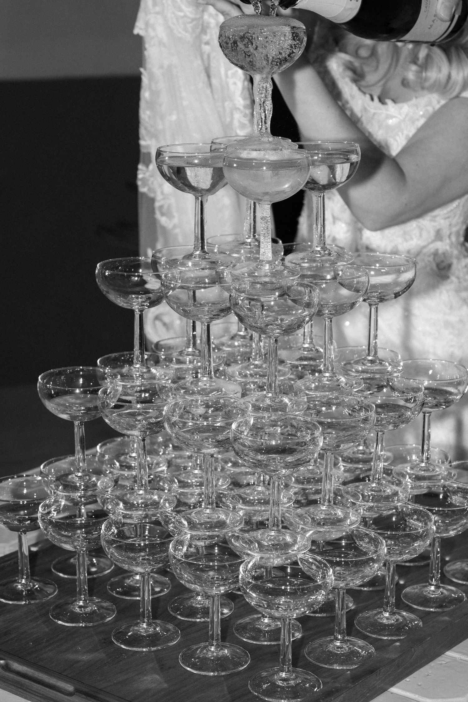 Champagne tower setup with multiple tiers of crystal coupe glasses ready for pouring.