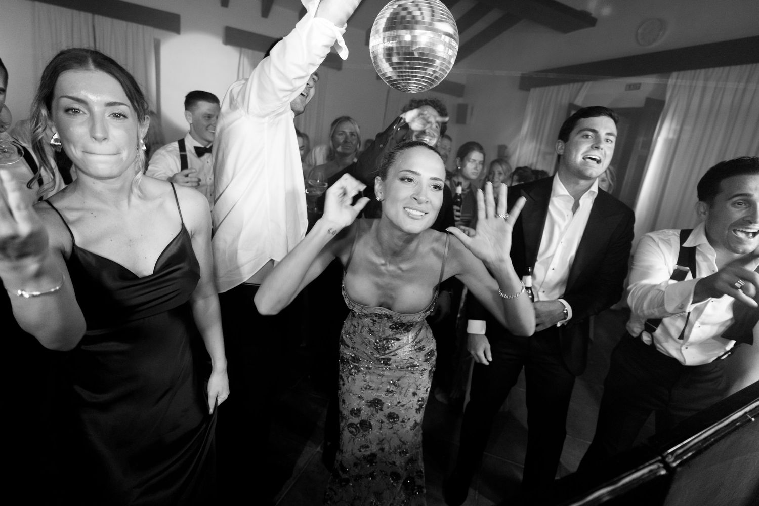 A collage of black and white party photos showing people dancing and celebrating at what appears to be a wedding reception.