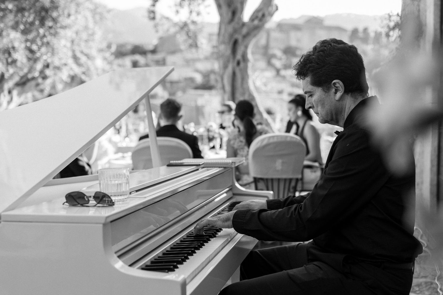 Piano player performs during an elegant wedding reception at a scenic Mediterranean venue.