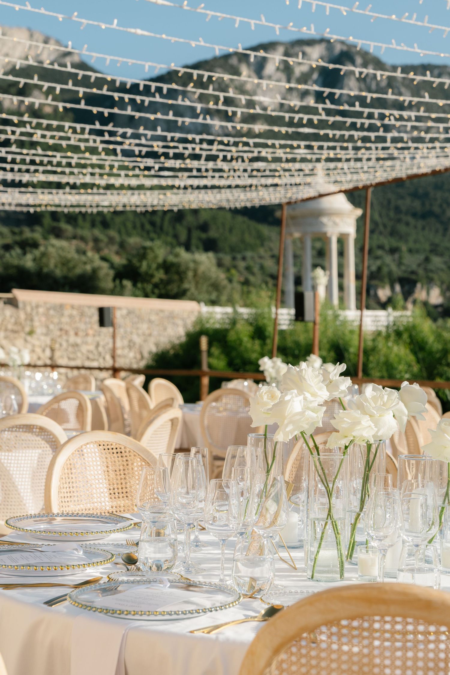 Elegant wedding reception tables decorated with string lights and mountain scenery in the background.