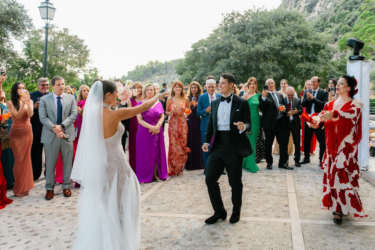 Wedding celebration with guests in colorful attire watching couple's first dance.