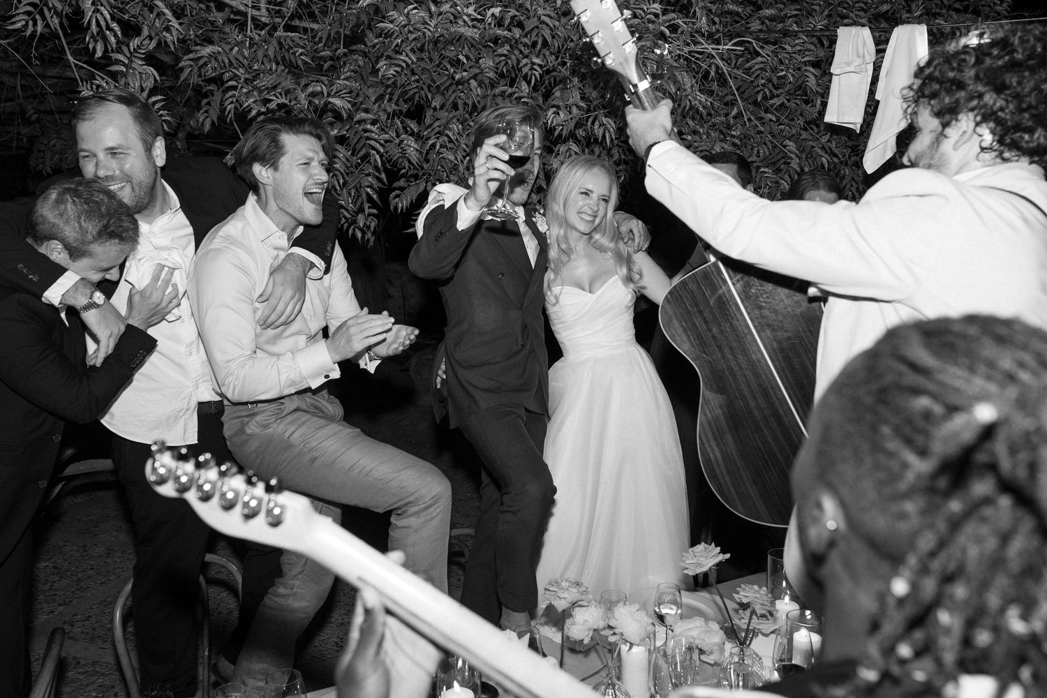 Wedding party guests dancing and celebrating in a dimly lit venue.