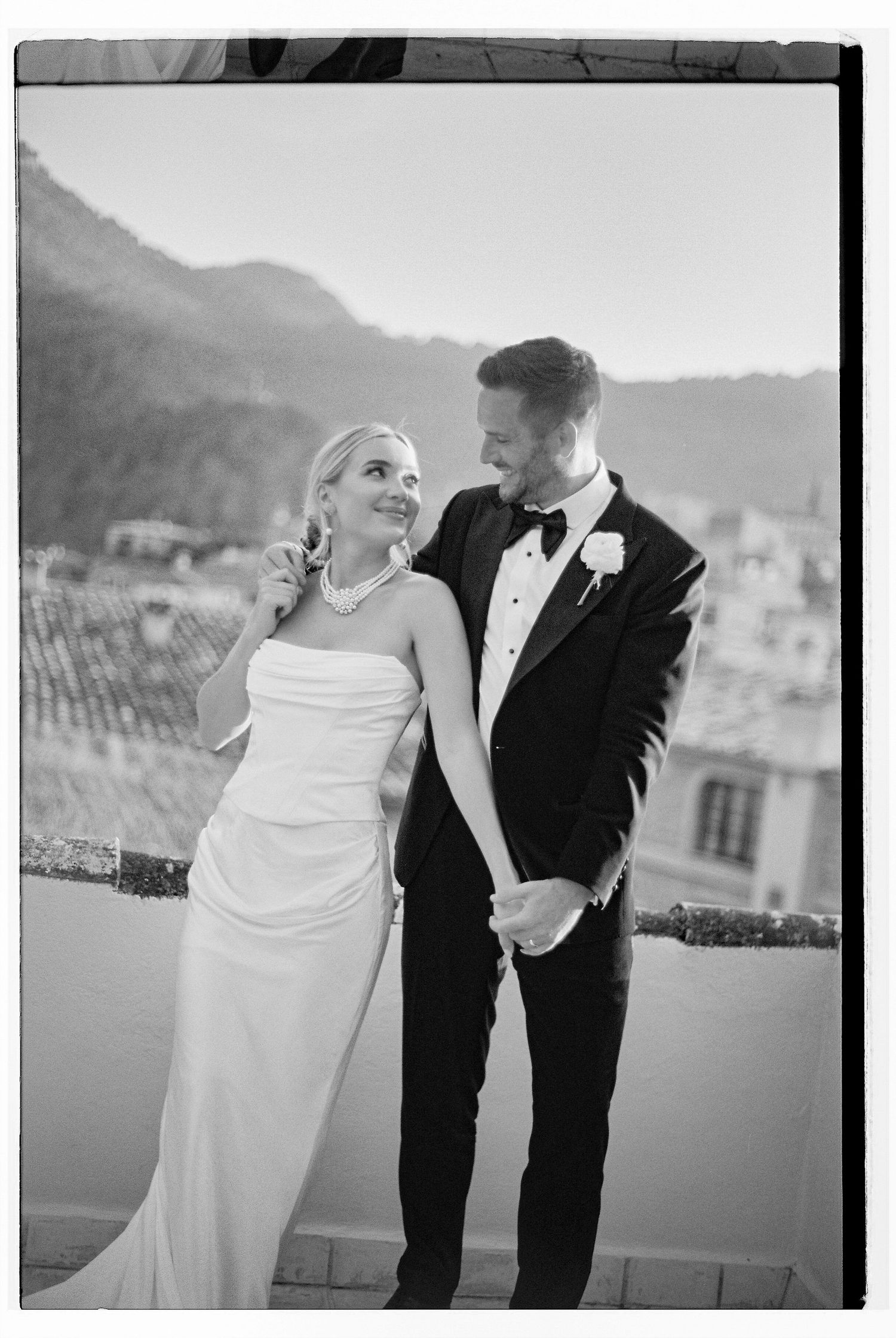 A couple shares a joyful moment together on a terrace with mountains in the background.