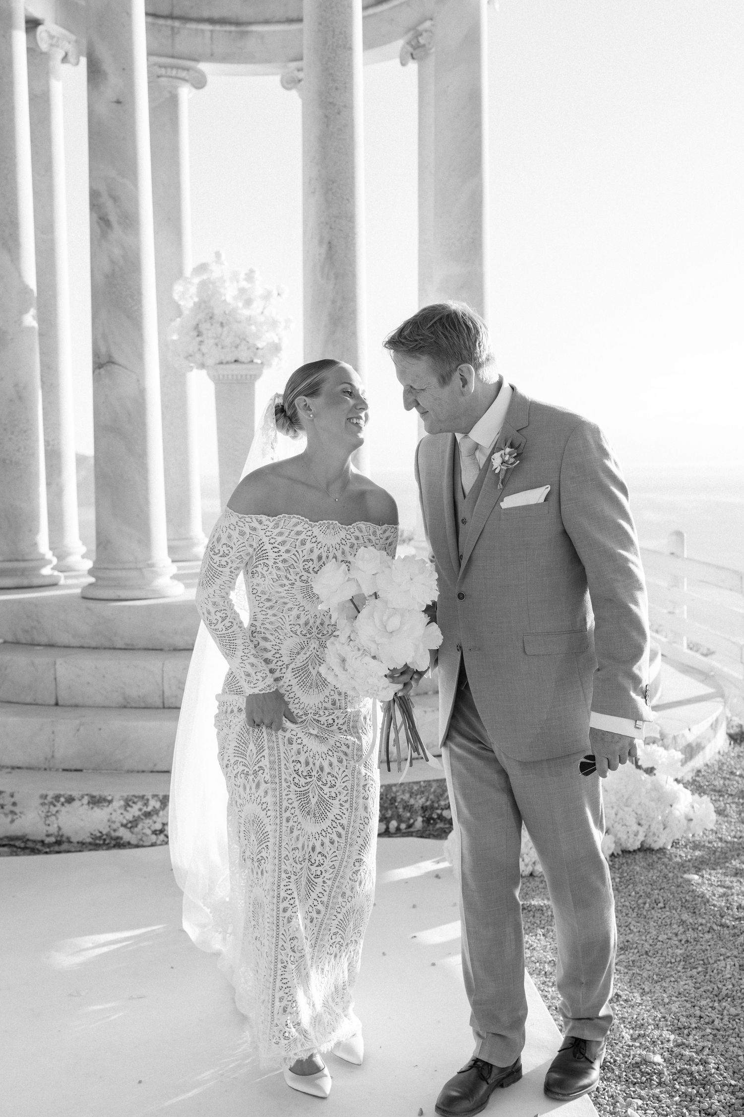 Intimate wedding portraits captured under ornate white marble columns with mountain backdrop.