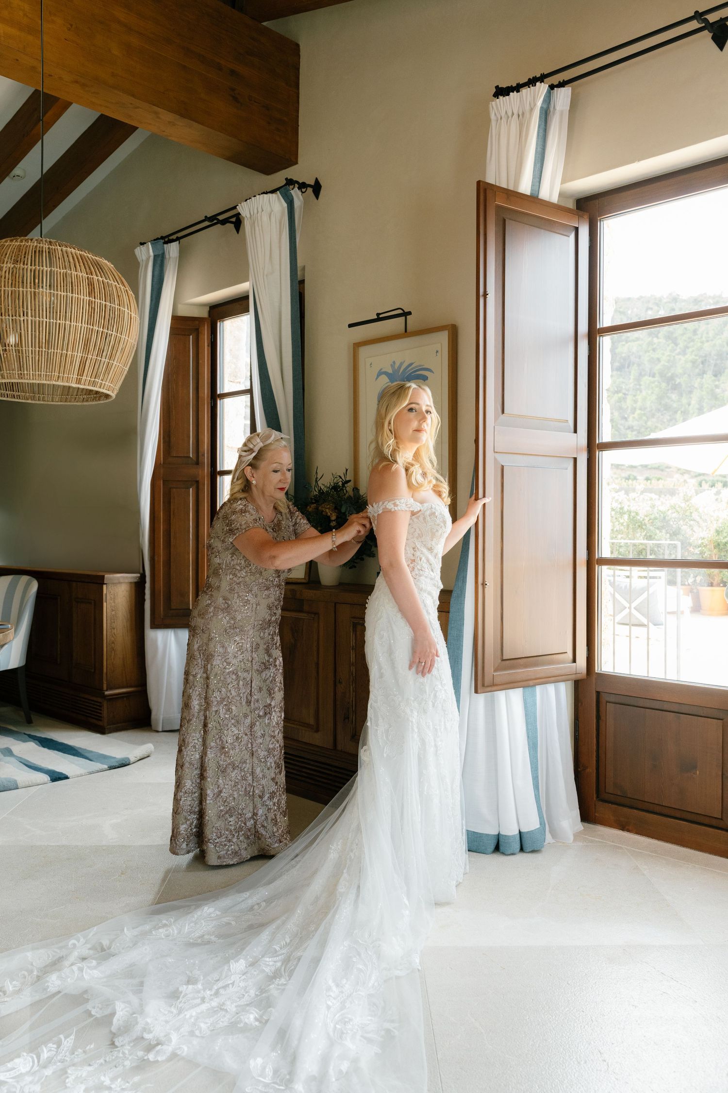 Wedding dress fitting in sunlit room with elegant lace gown.