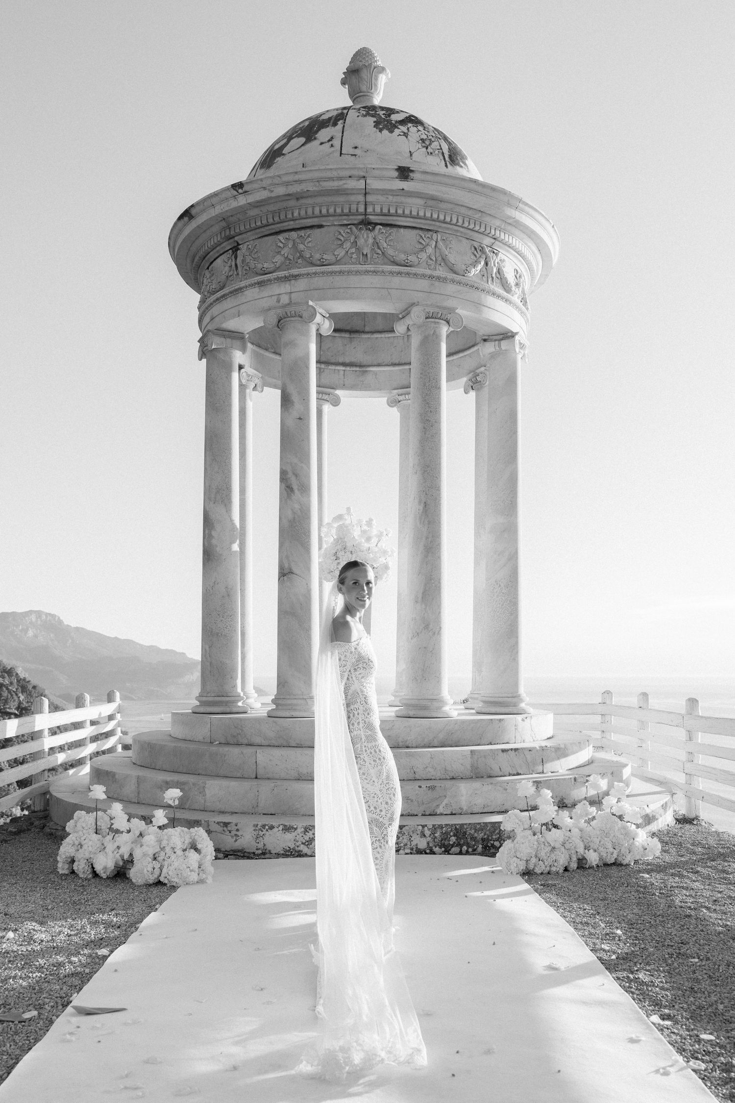 Ethereal bridal portraits in white marble gazebo with dramatic mountain landscape.