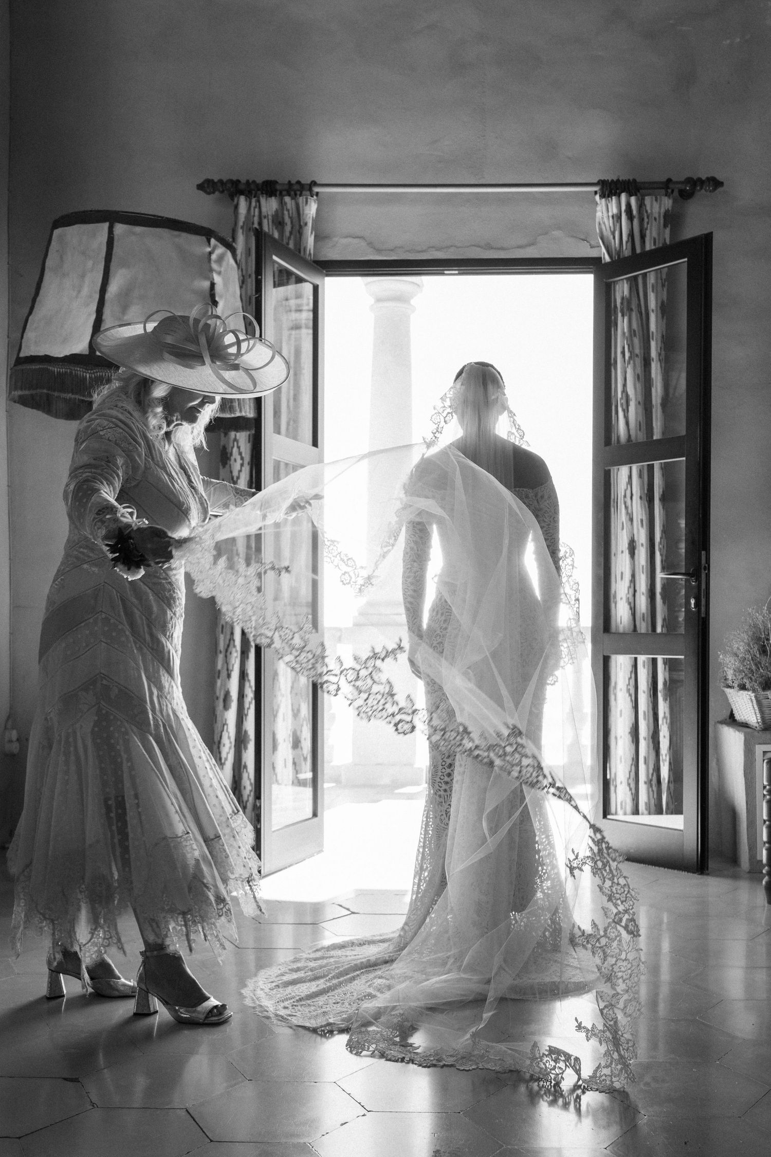 Wedding dress preparation captured in dramatic black and white photography.