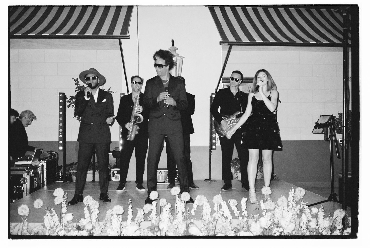 Black and white photo of a band performing on stage with decorative lights.