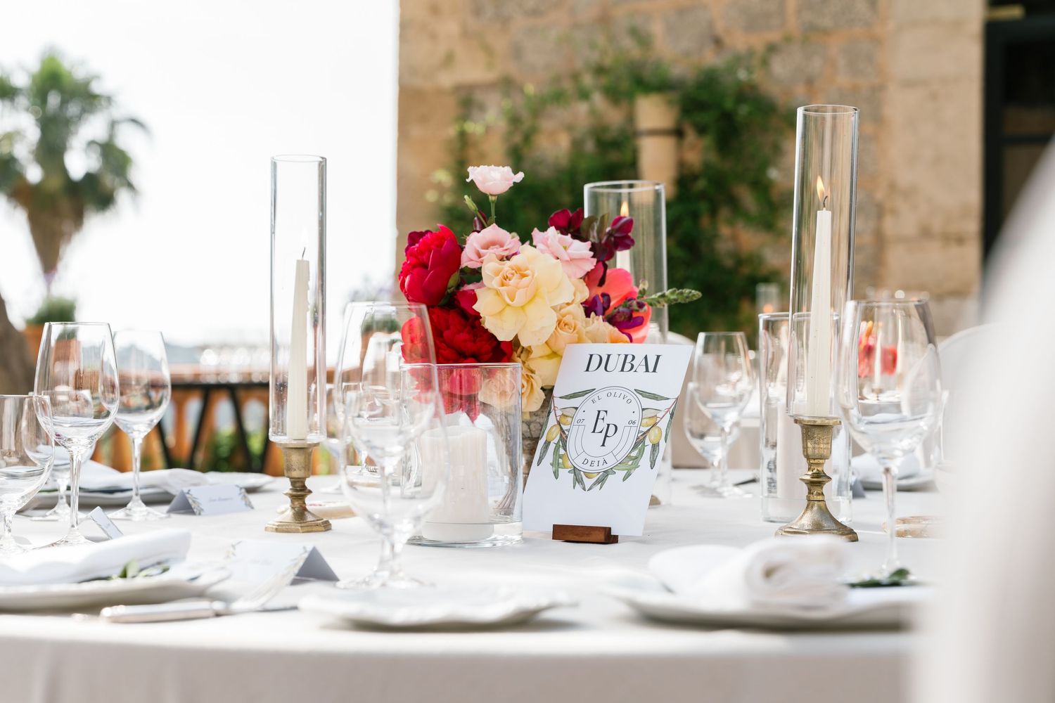 Elegant wedding reception table settings with crystal glasses and floral centerpieces at a Mediterranean venue.
