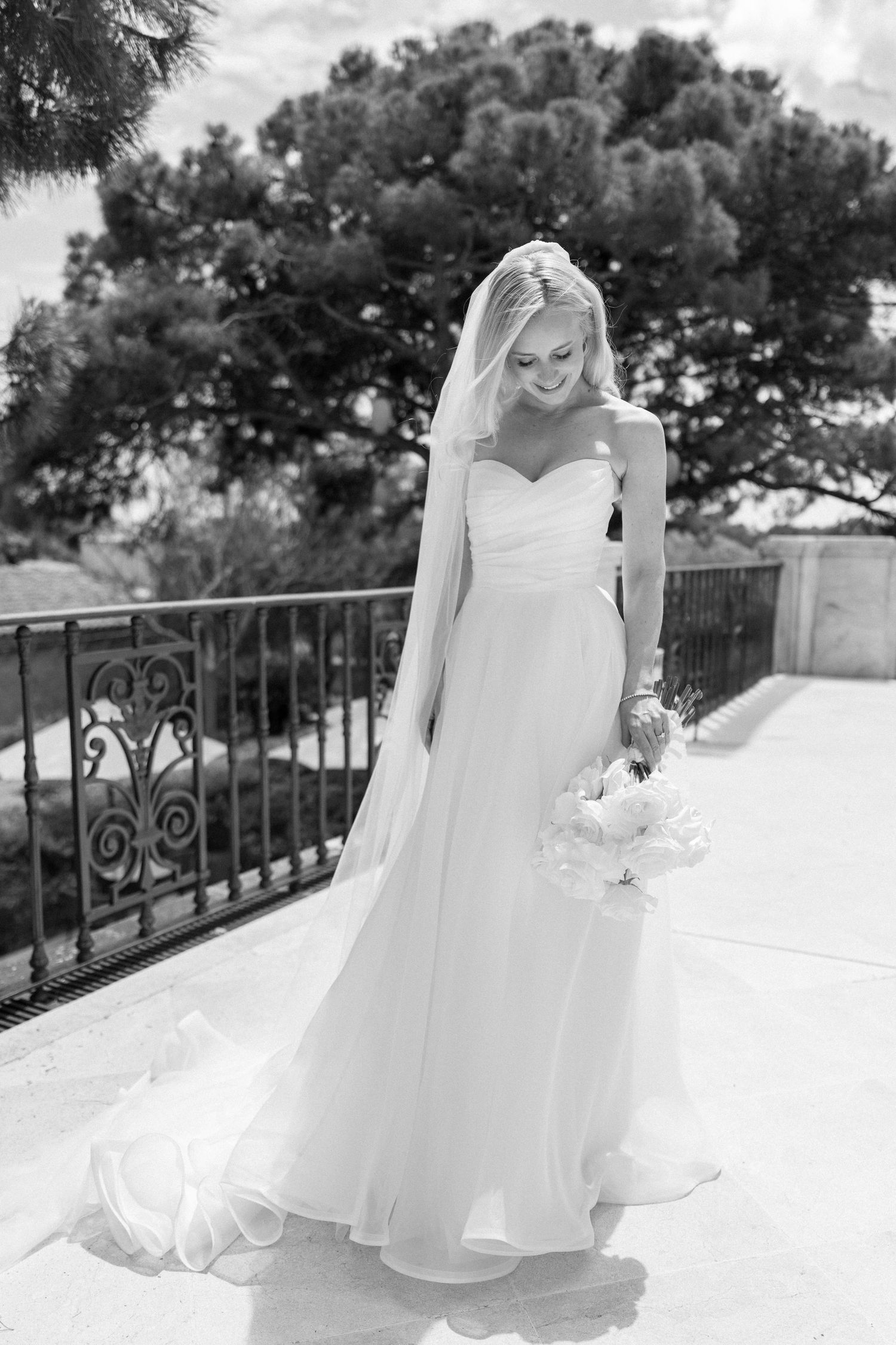 A flowing white wedding dress twirls gracefully against an outdoor balcony backdrop.