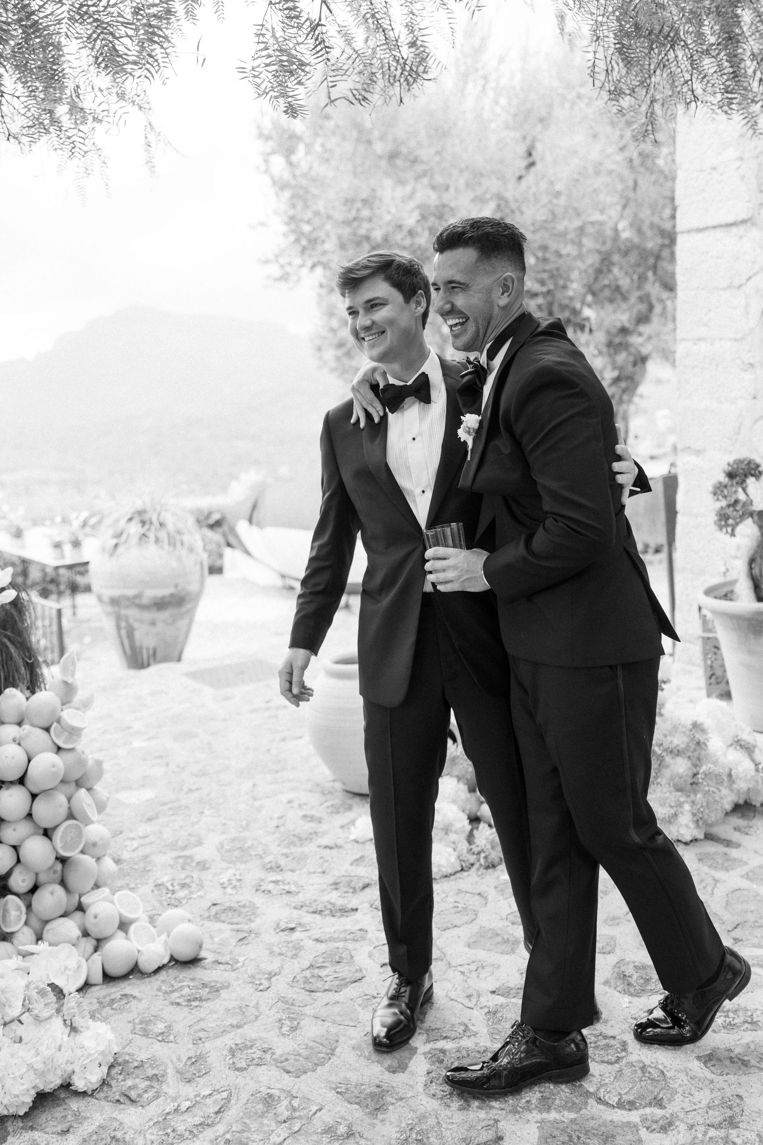 Two people in black tuxedos share playful moments in a series of black and white wedding photos.