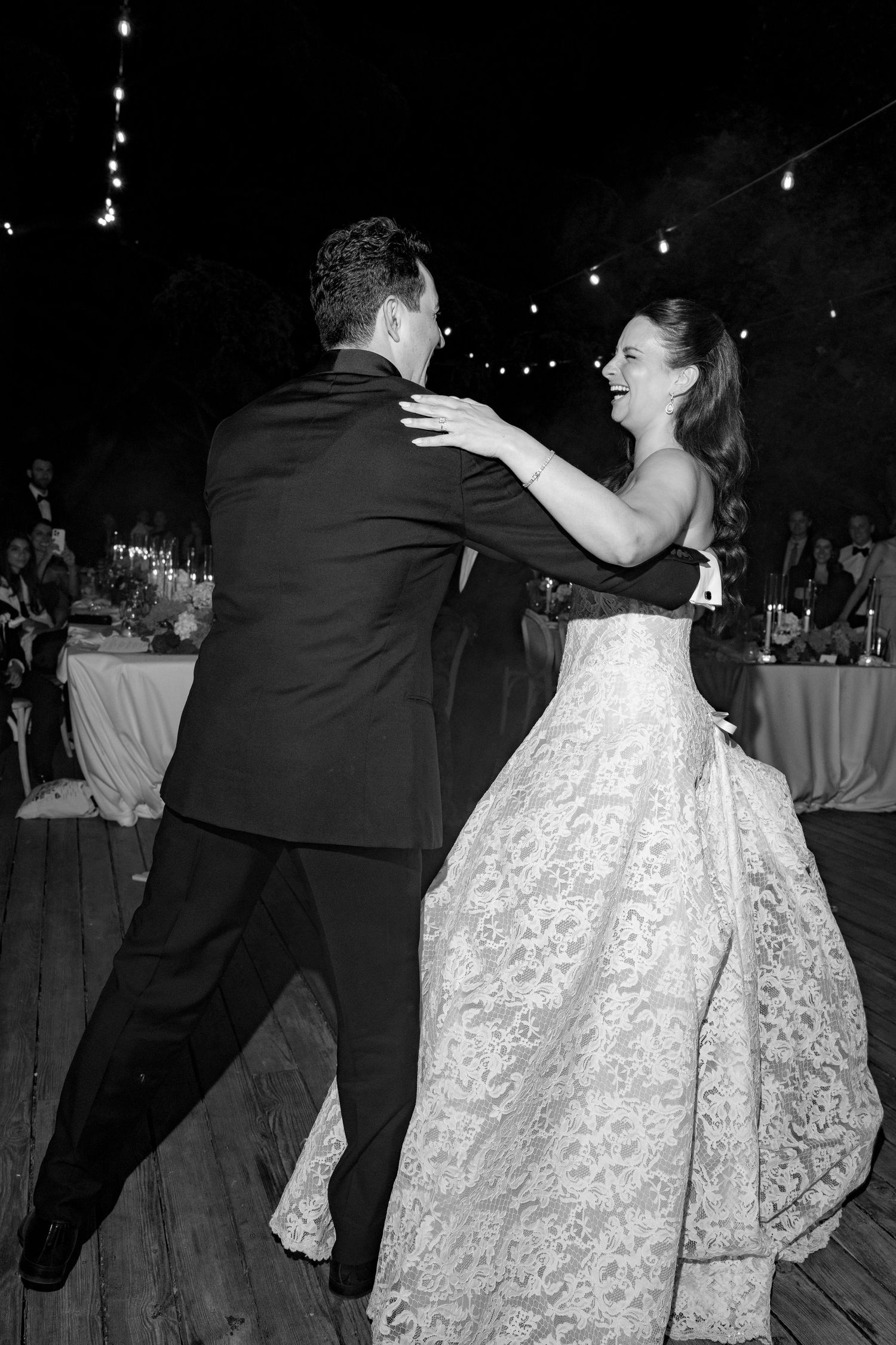 Black and white photo of a bride and groom sharing their first dance at an outdoor wedding reception.