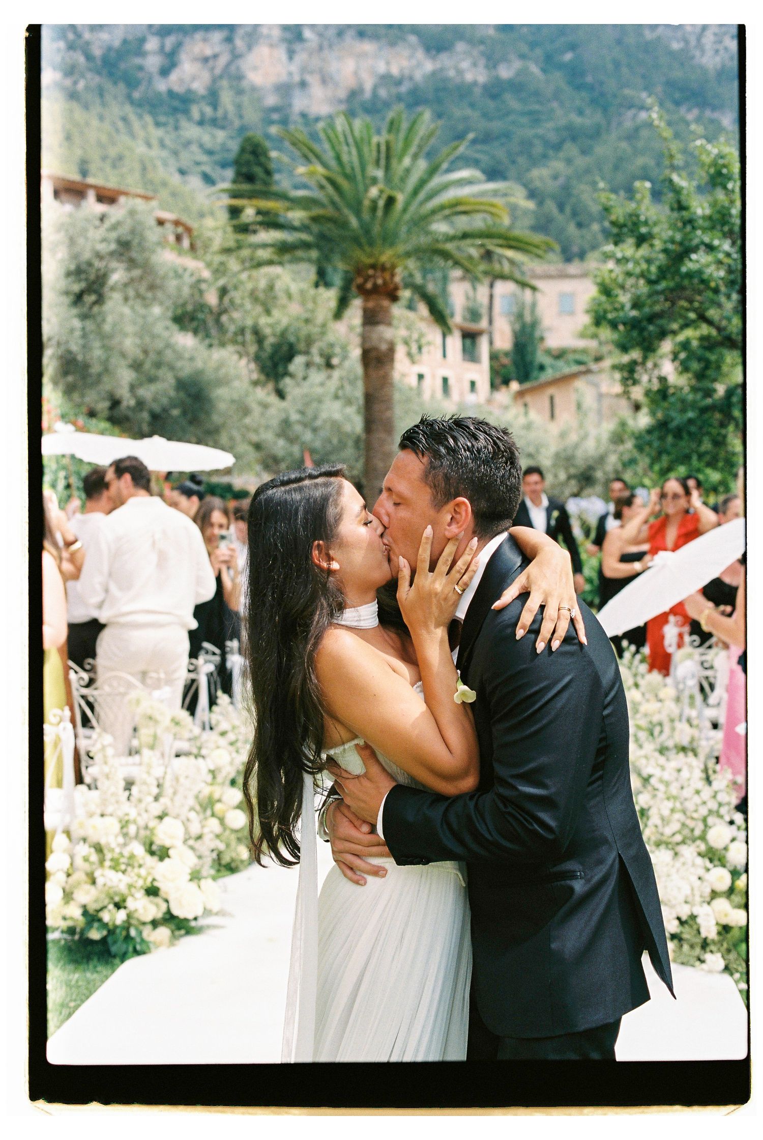 Romantic wedding kiss in garden with palm trees and mountain backdrop at Belmond La Residencia.