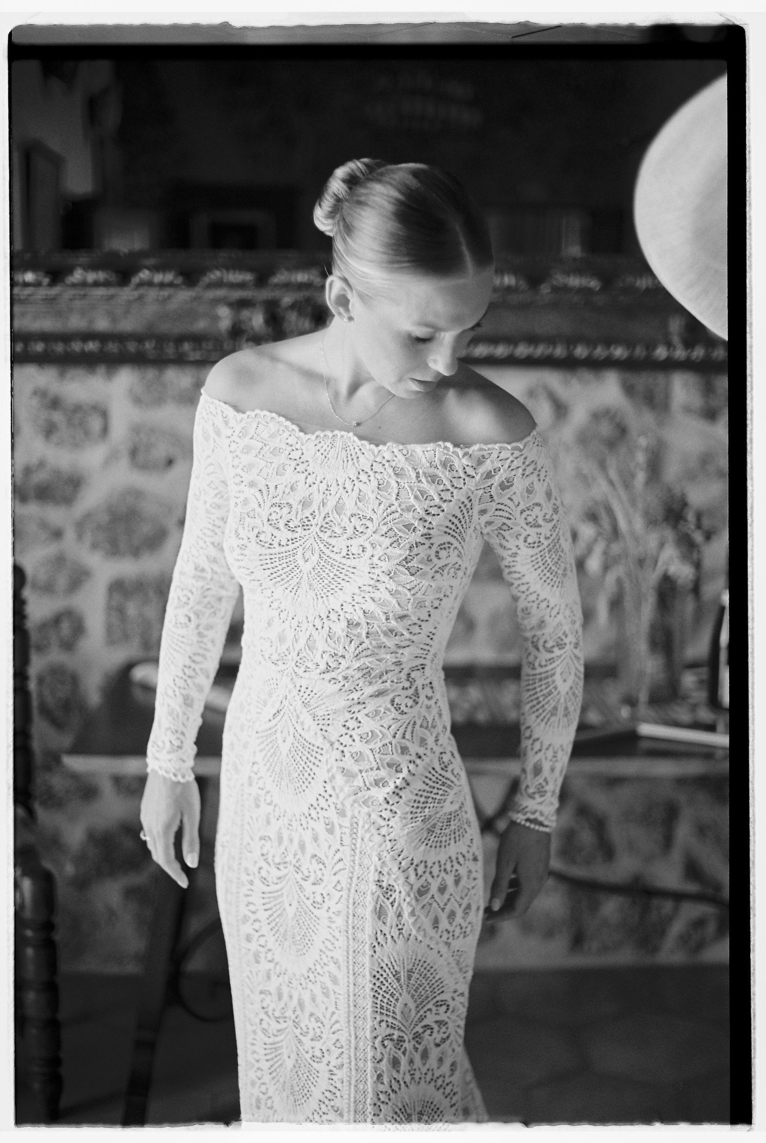 Close-up detail of intricate lace wedding dress with off-shoulder neckline.