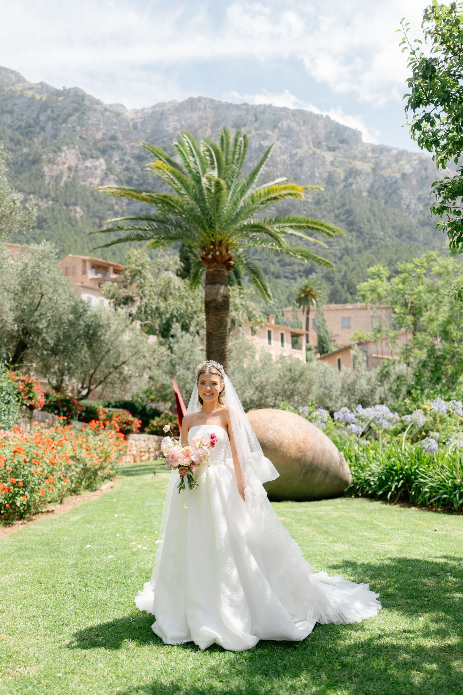 Elegant bridal portraits in garden setting with palm trees and mountain backdrop.