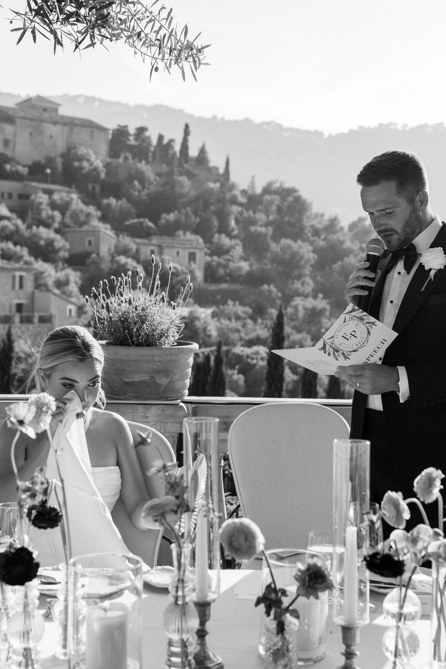 Outdoor wedding reception tables decorated with white linens and floral centerpieces against a mountain backdrop.
