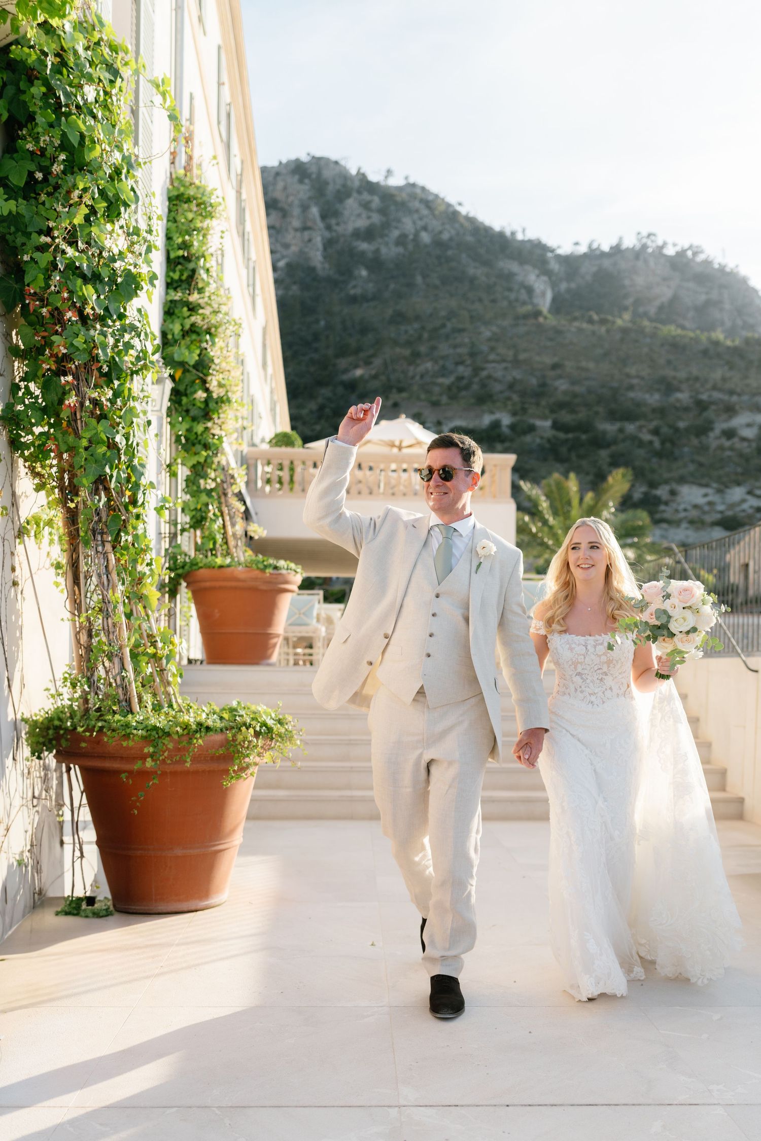 Wedding couple dancing and celebrating on a sunny terrace with mountain views.