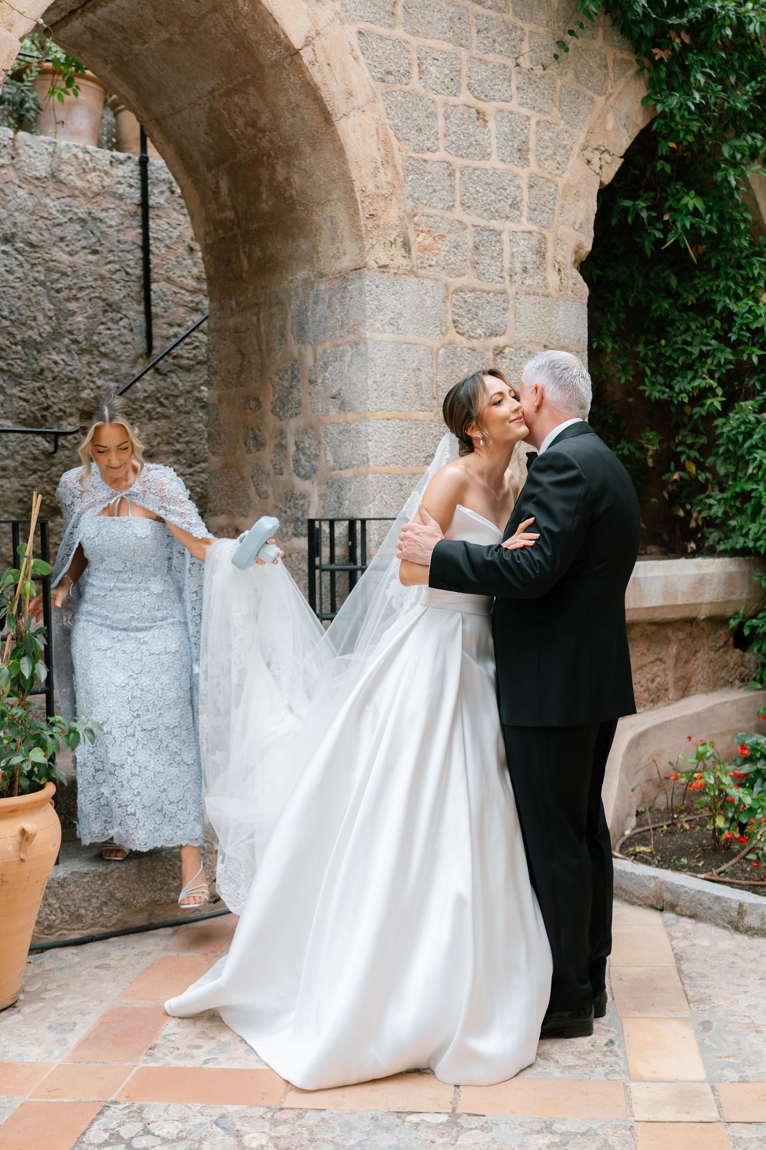 Romantic wedding couple posing under stone archways at Mediterranean villa.
