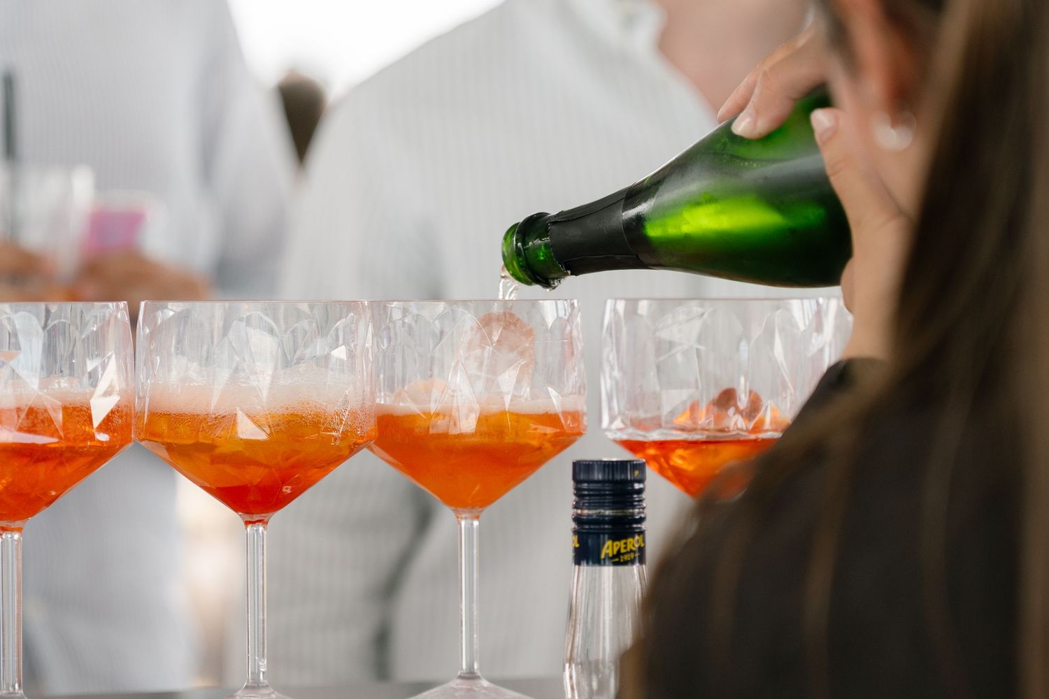 Champagne being poured into elegant glasses at an upscale waterfront event.