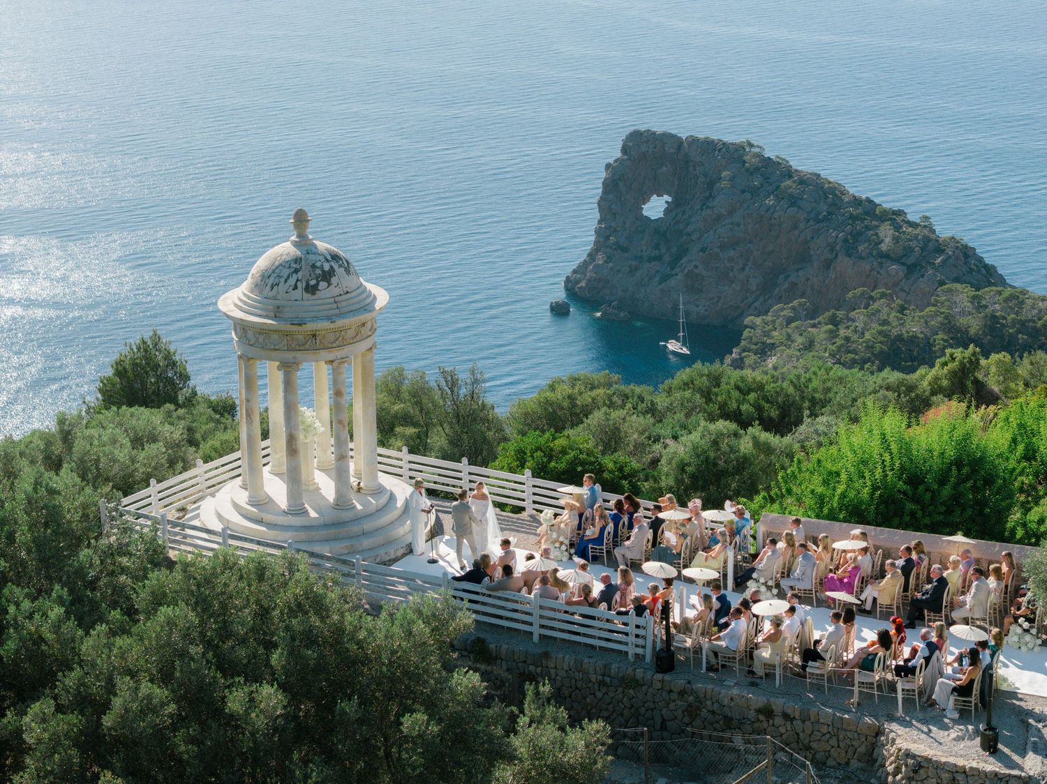 Panoramic coastal view of a Mediterranean landscape with a white domed structure overlooking the sea.