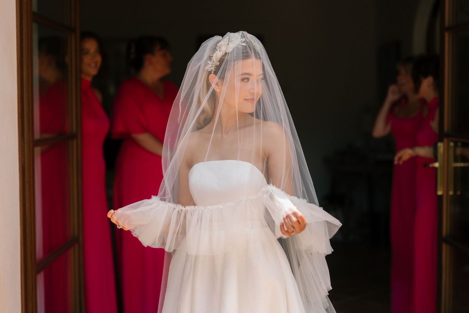 Bride in cathedral veil walks through dramatic church interior.