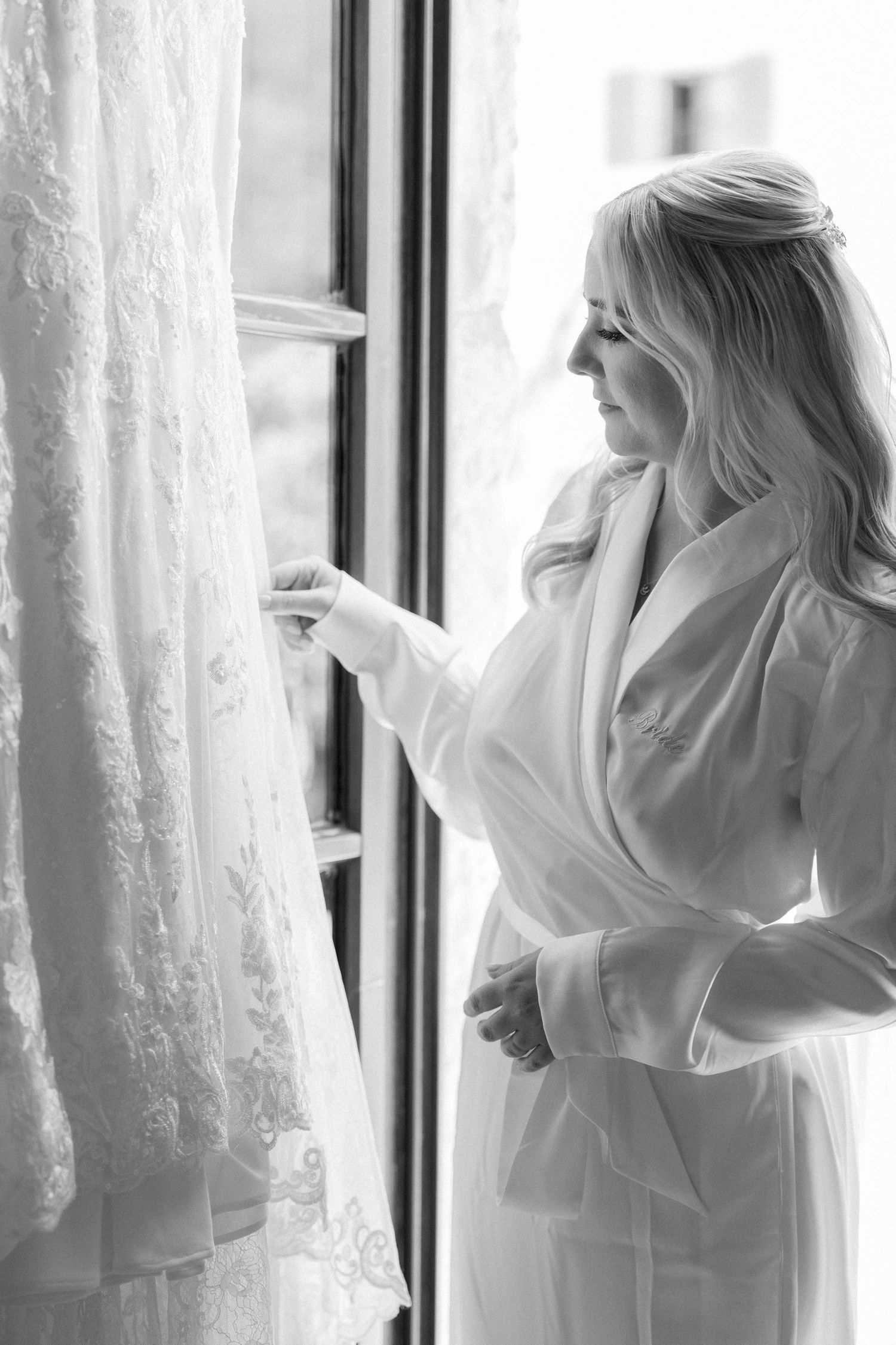Silhouette by window with flowing white curtains and wedding dress.