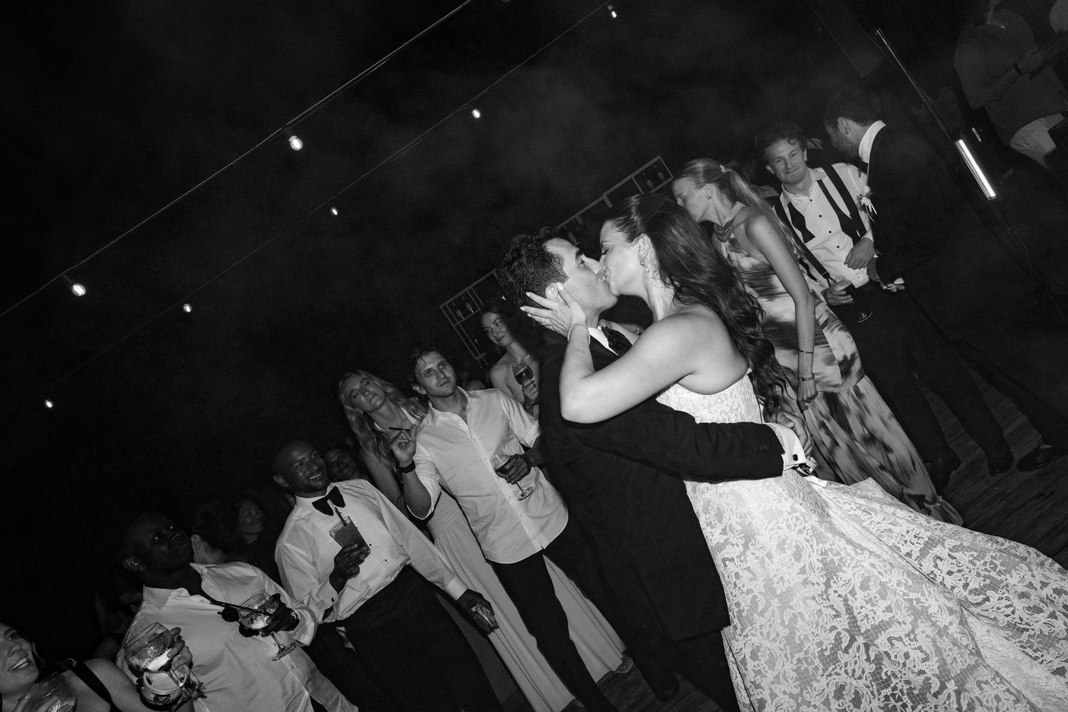 Black and white photo of a couple sharing a first dance kiss at their wedding reception.