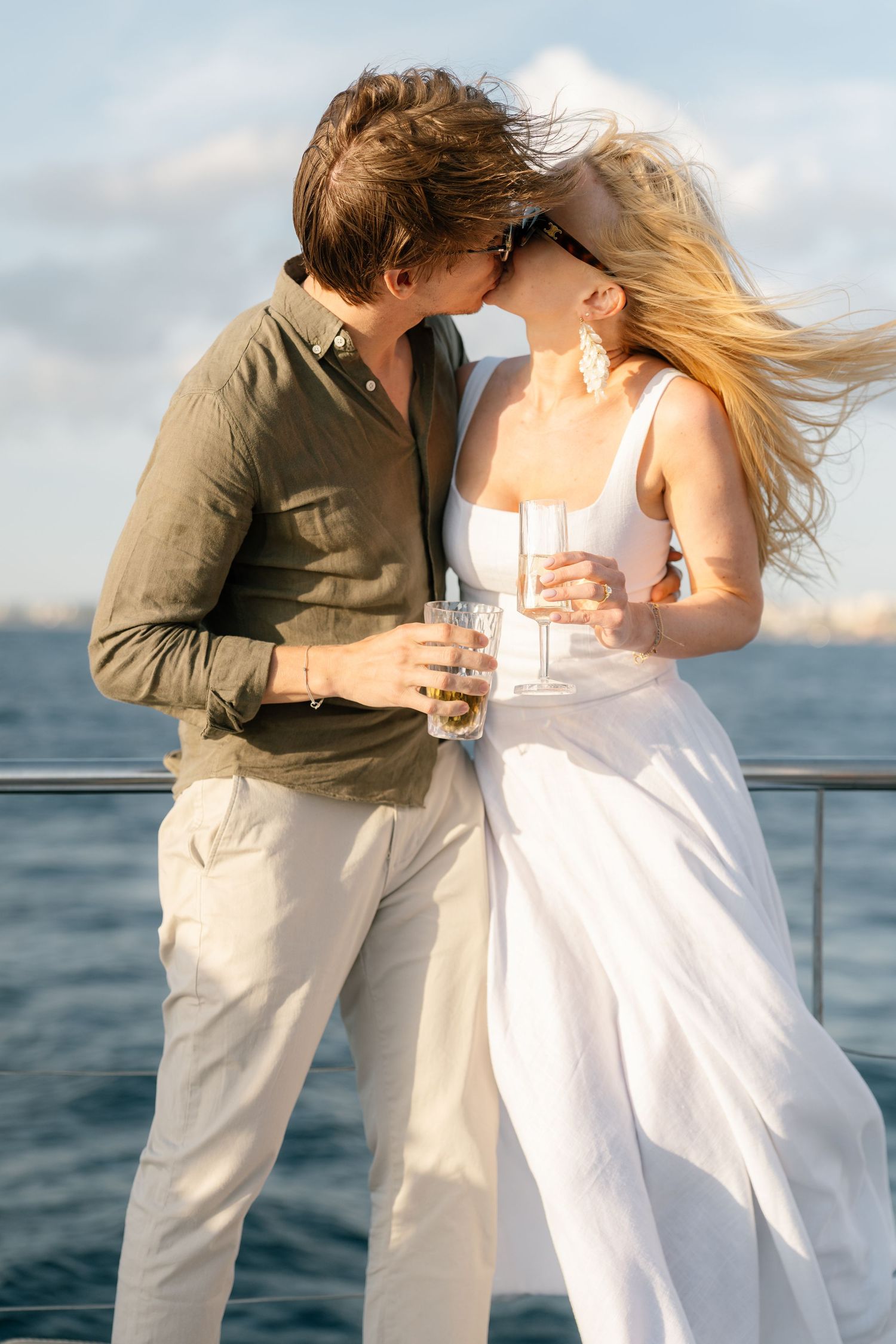 A romantic couple shares an intimate moment at sunset on a boat deck by the ocean.