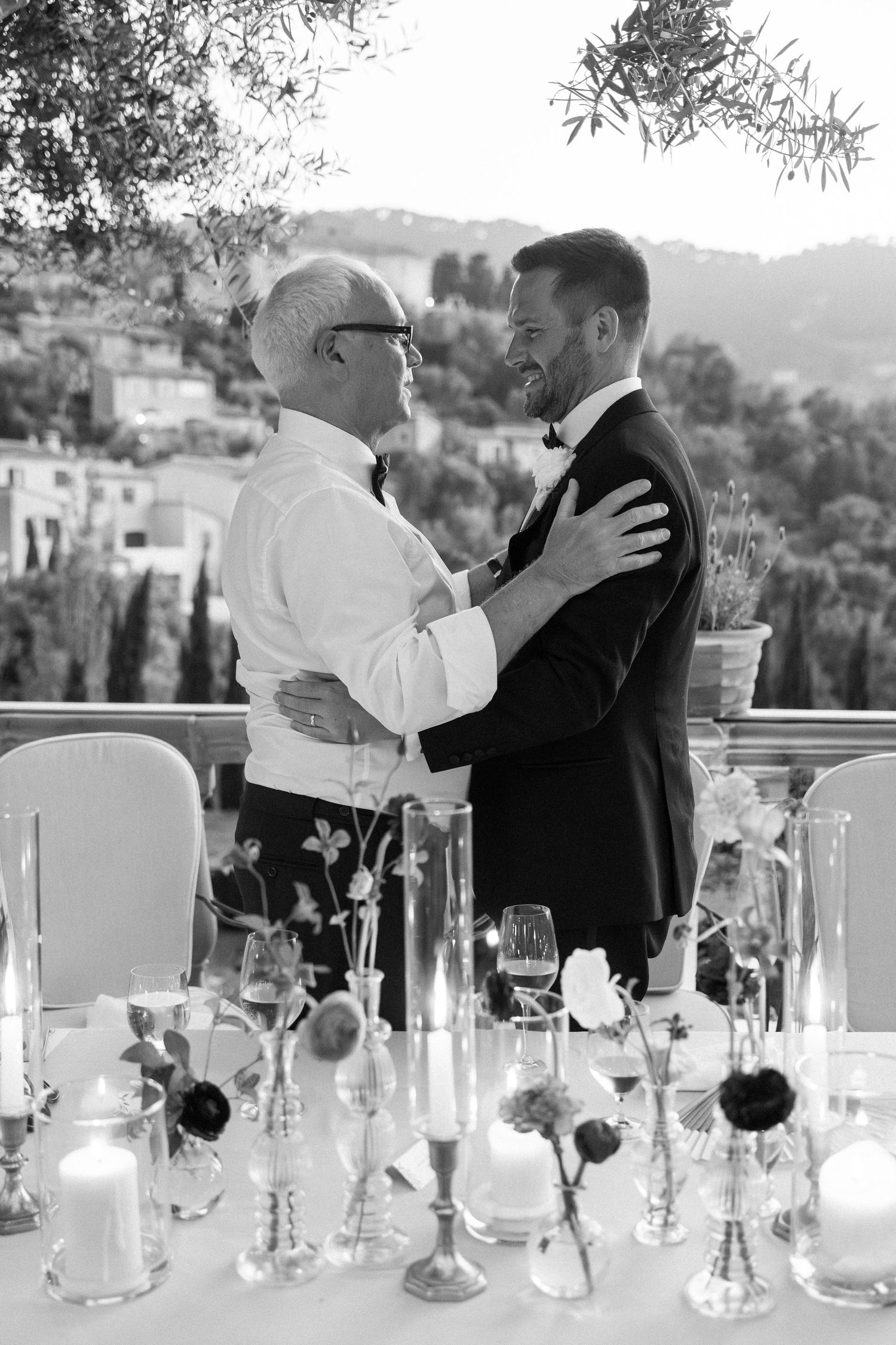 Wedding couple dancing among elegant glass centerpieces at outdoor reception.