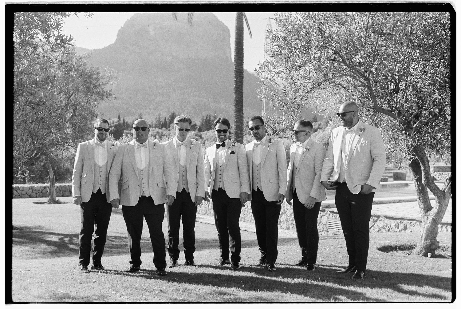 Wedding party members lined up outdoors in formal attire.