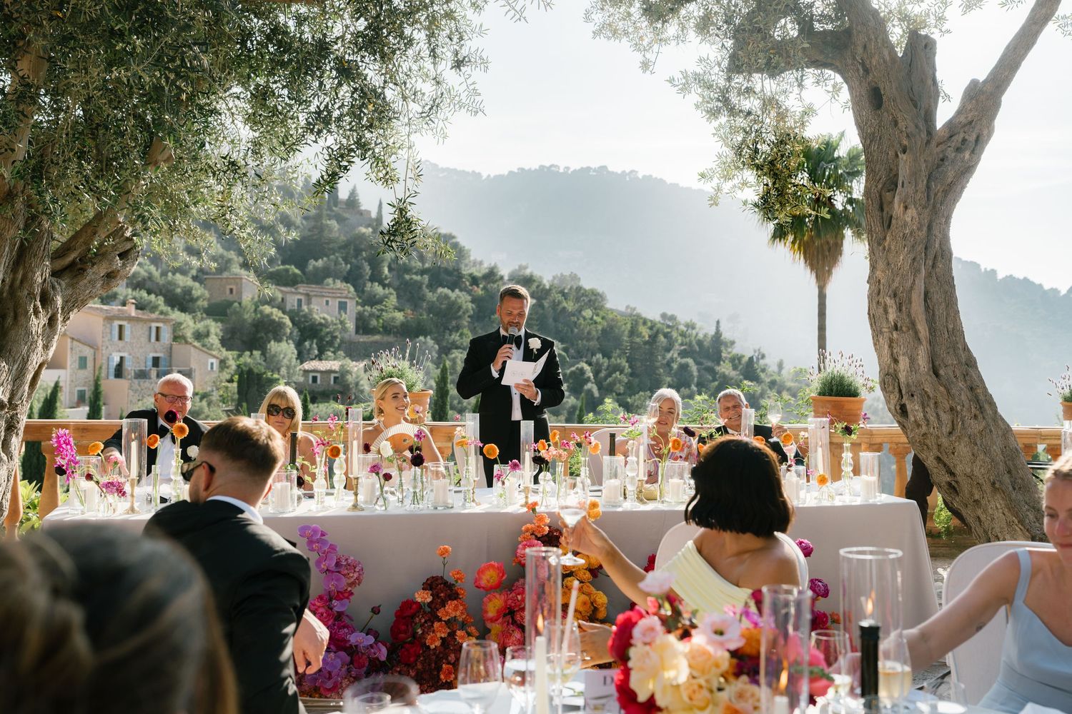 Beautiful outdoor wedding reception setup with mountain views and palm trees in the background.