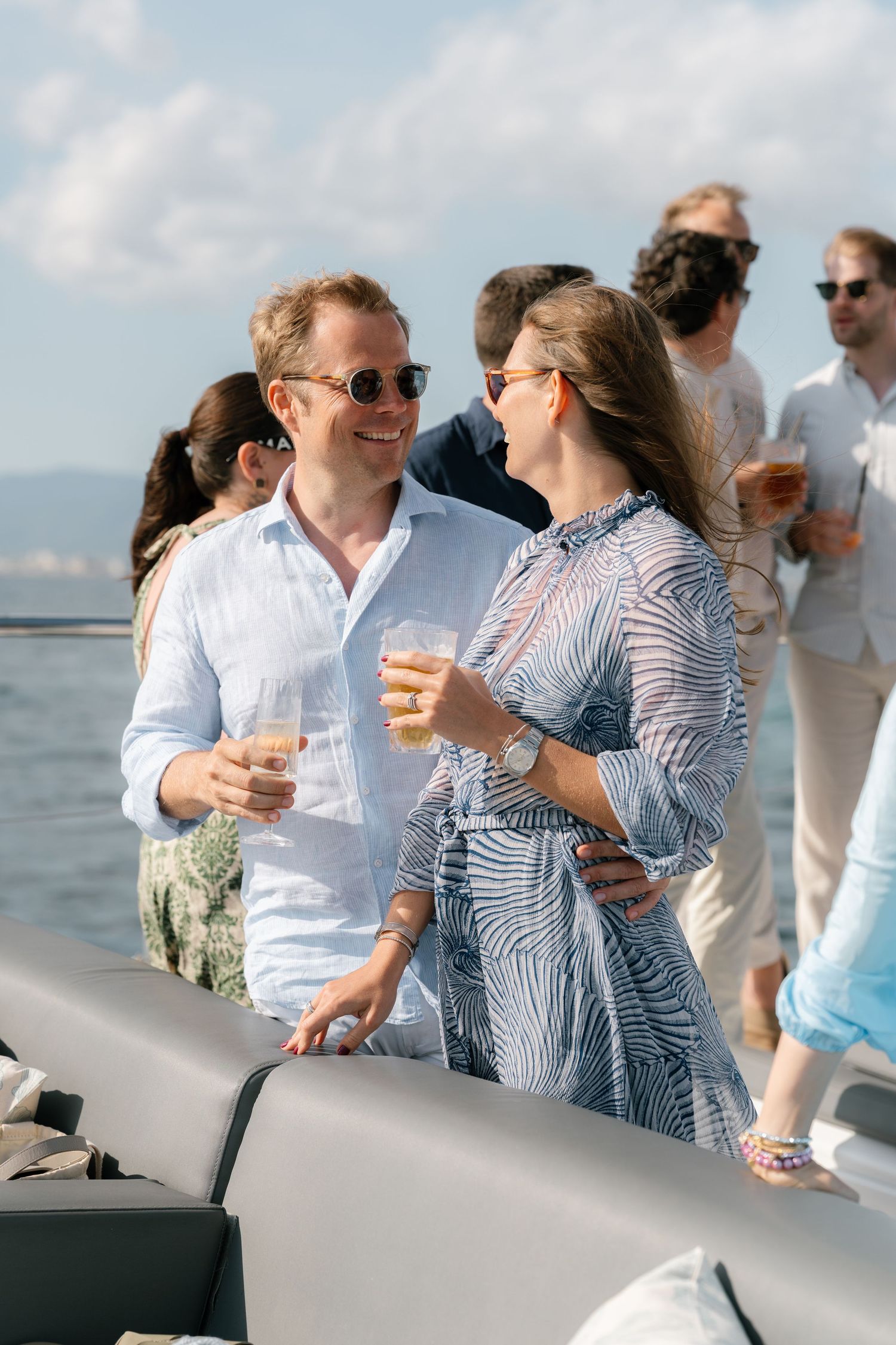 Guests in light summer clothing socializing during a waterfront celebration.