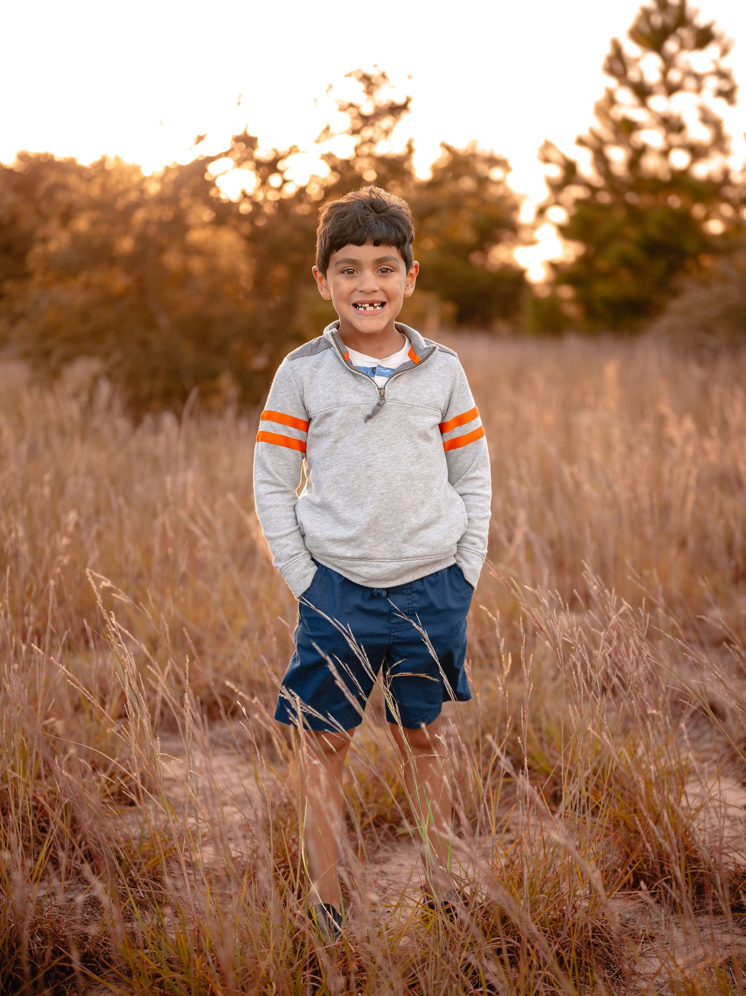 boy standing in tall grass at sunset, Chesapeake VA fall mini session photographer.