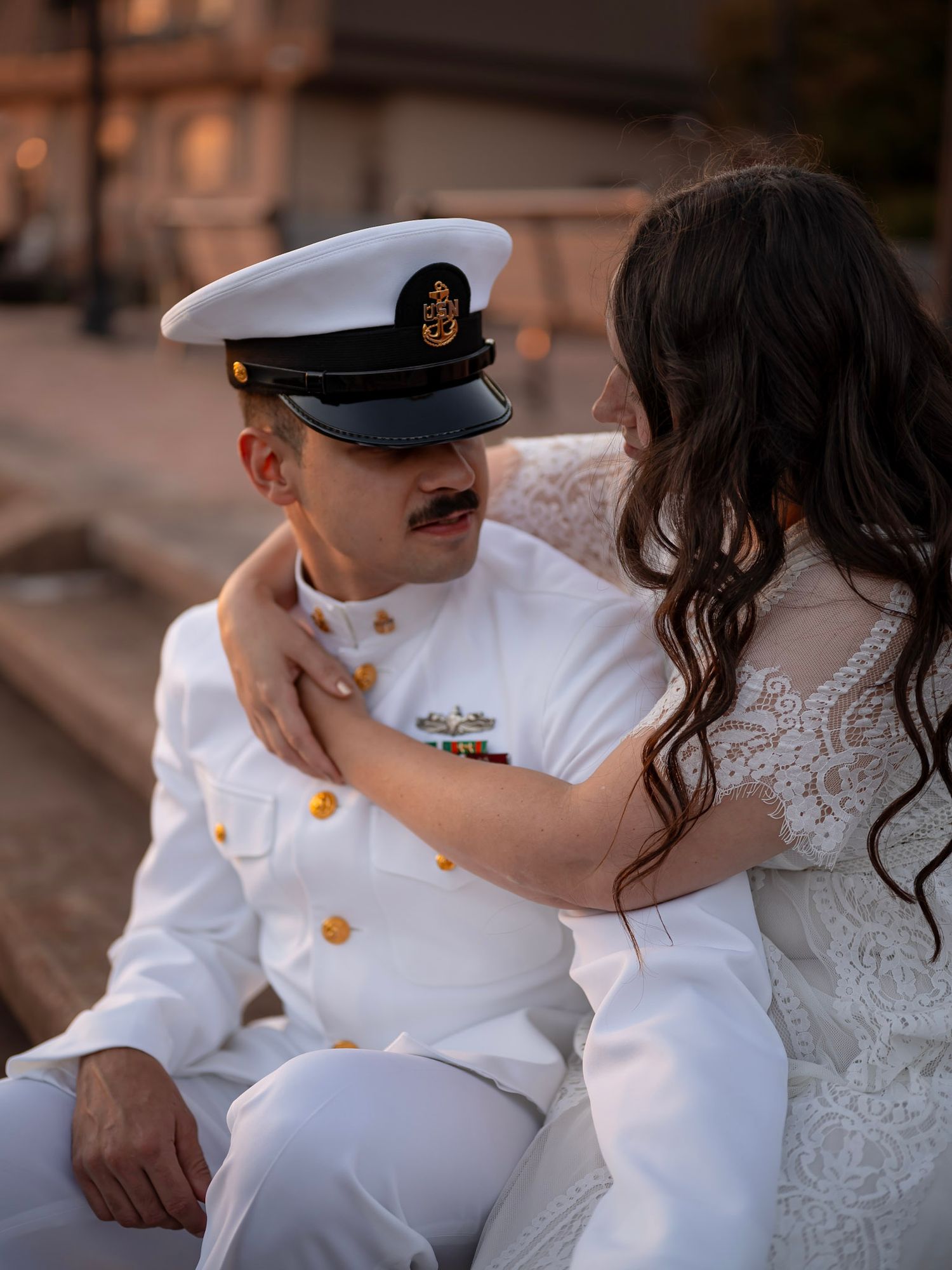 Navy sailor in uniform embraced by his partner for a kiss by the pier -romantic military couples